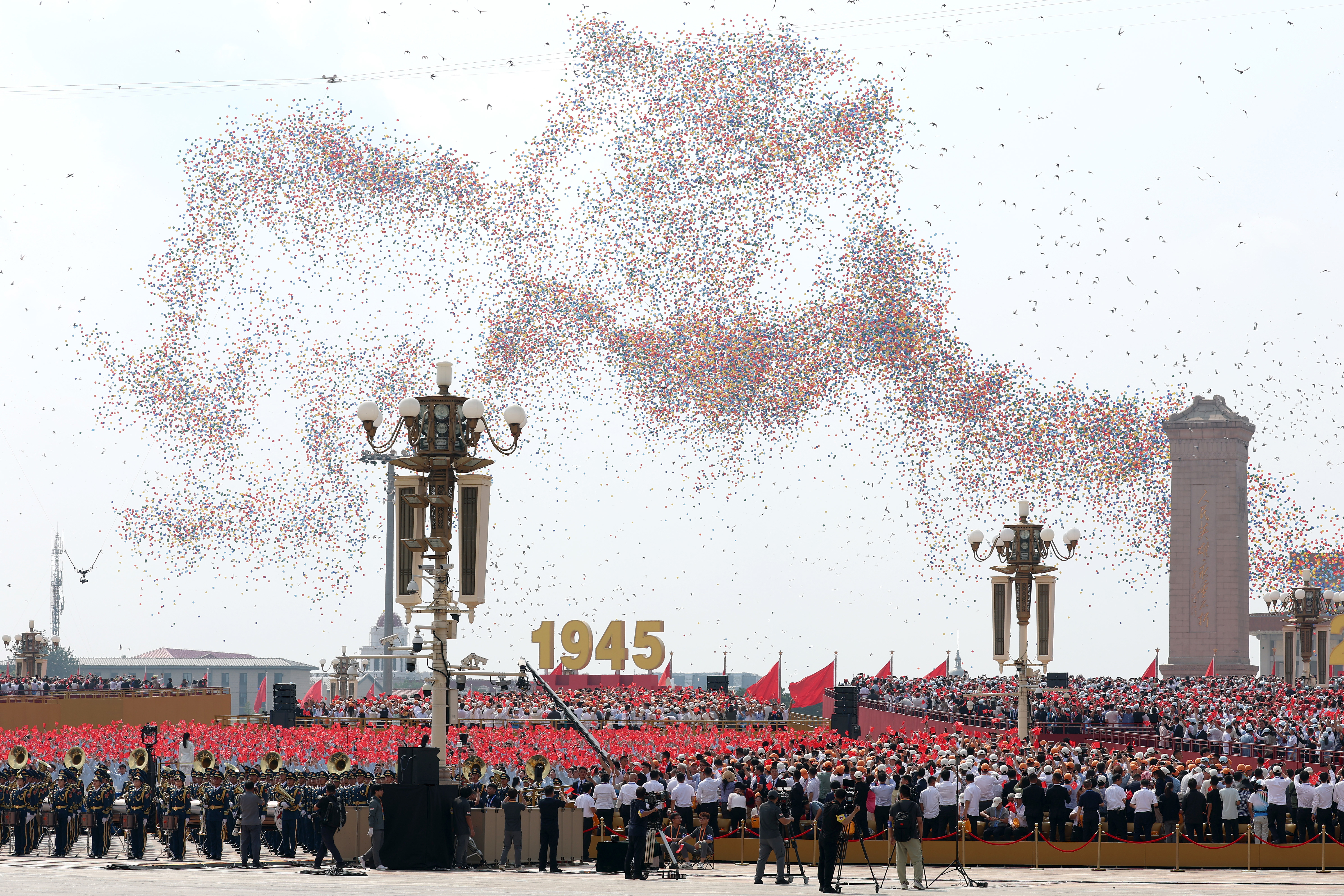 Balloons and doves are released into the air during the military parade.
