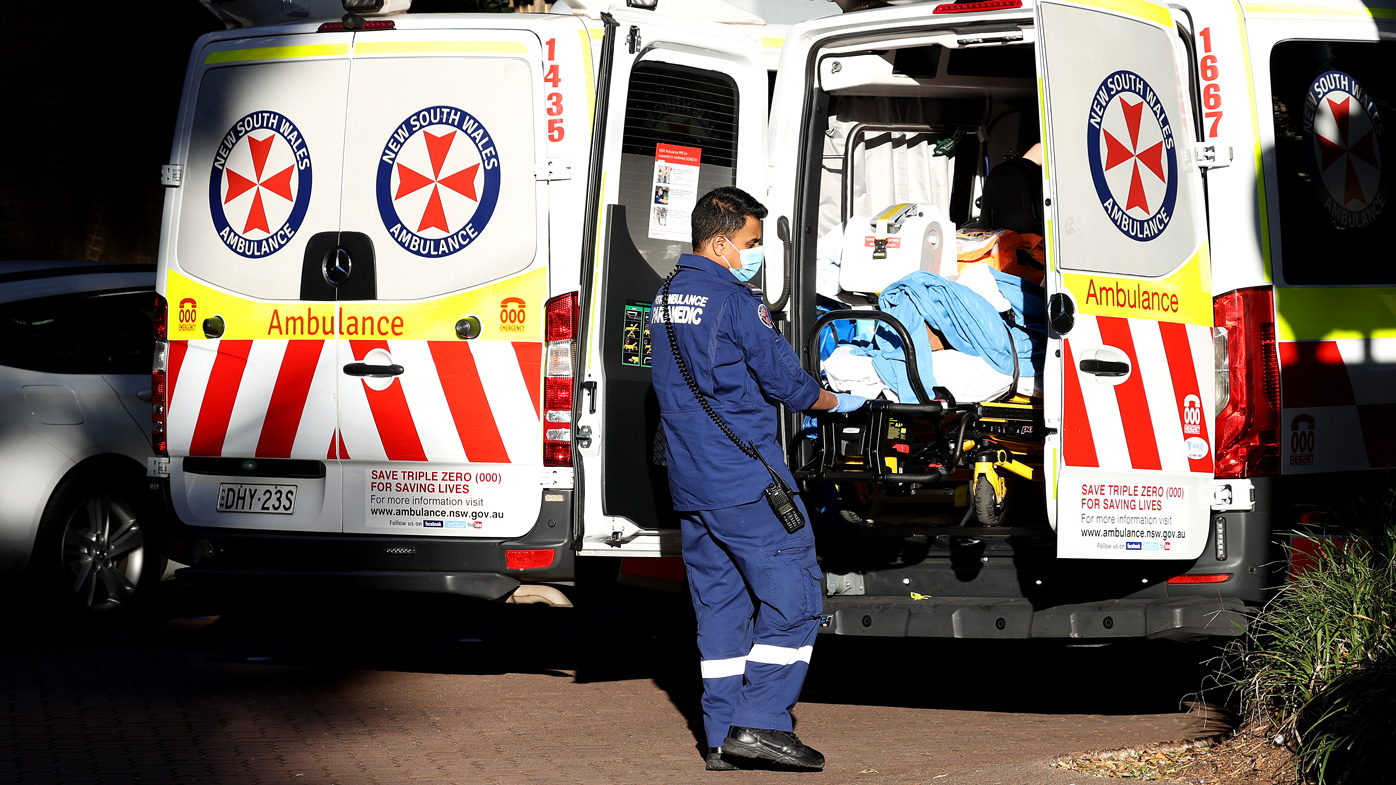 A NSW ambulance paramedic helps a patient into a Sydney hospital.