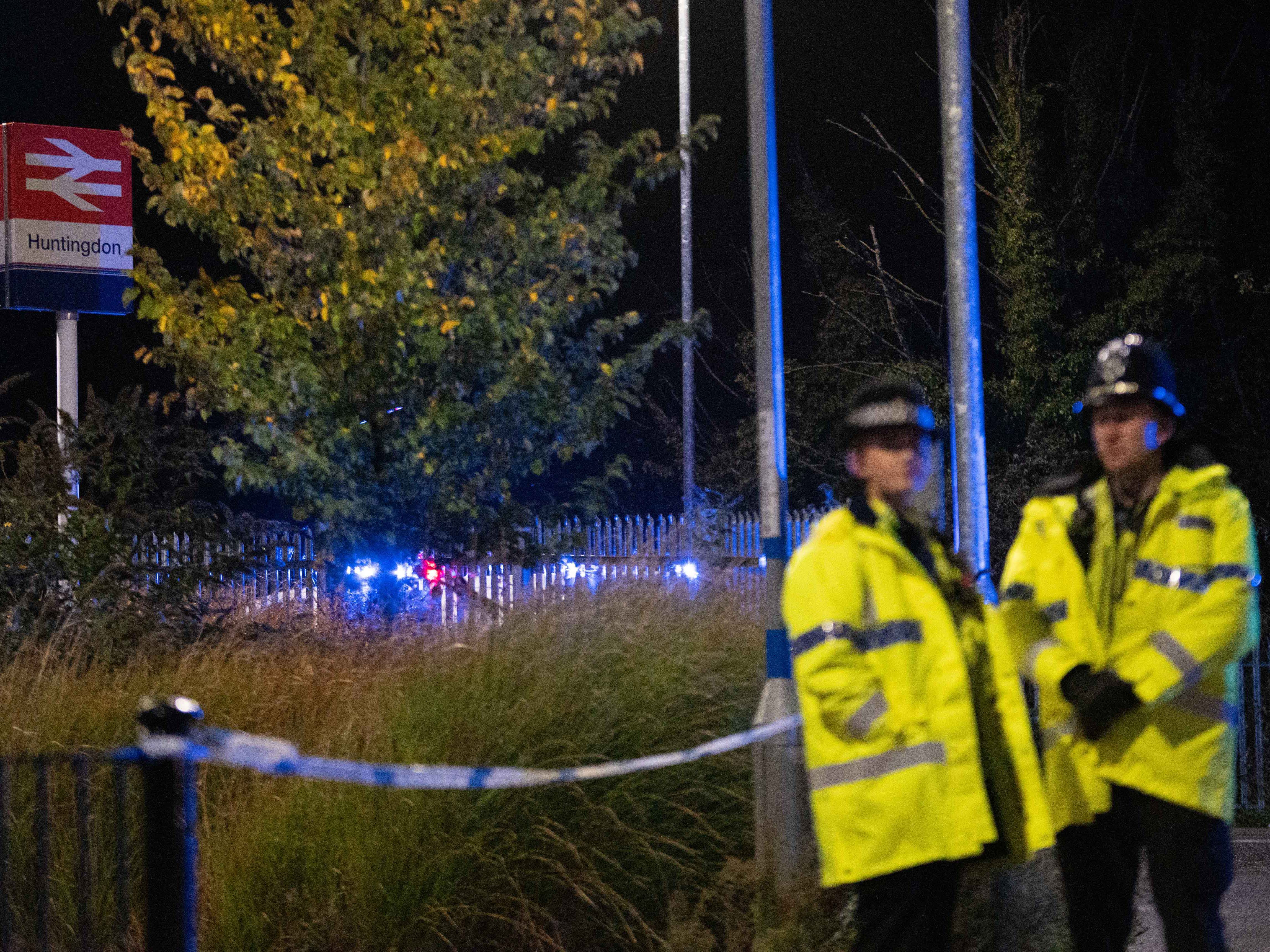 Police officers stand near a cordon outside Huntingdon Station  where the train stopped after the attack
