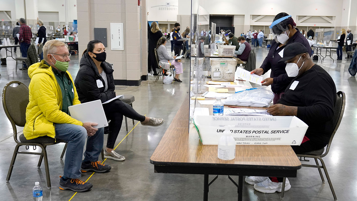 Election workers verify ballots as recount observers, left, watch during a Milwaukee hand recount of presidential votes.