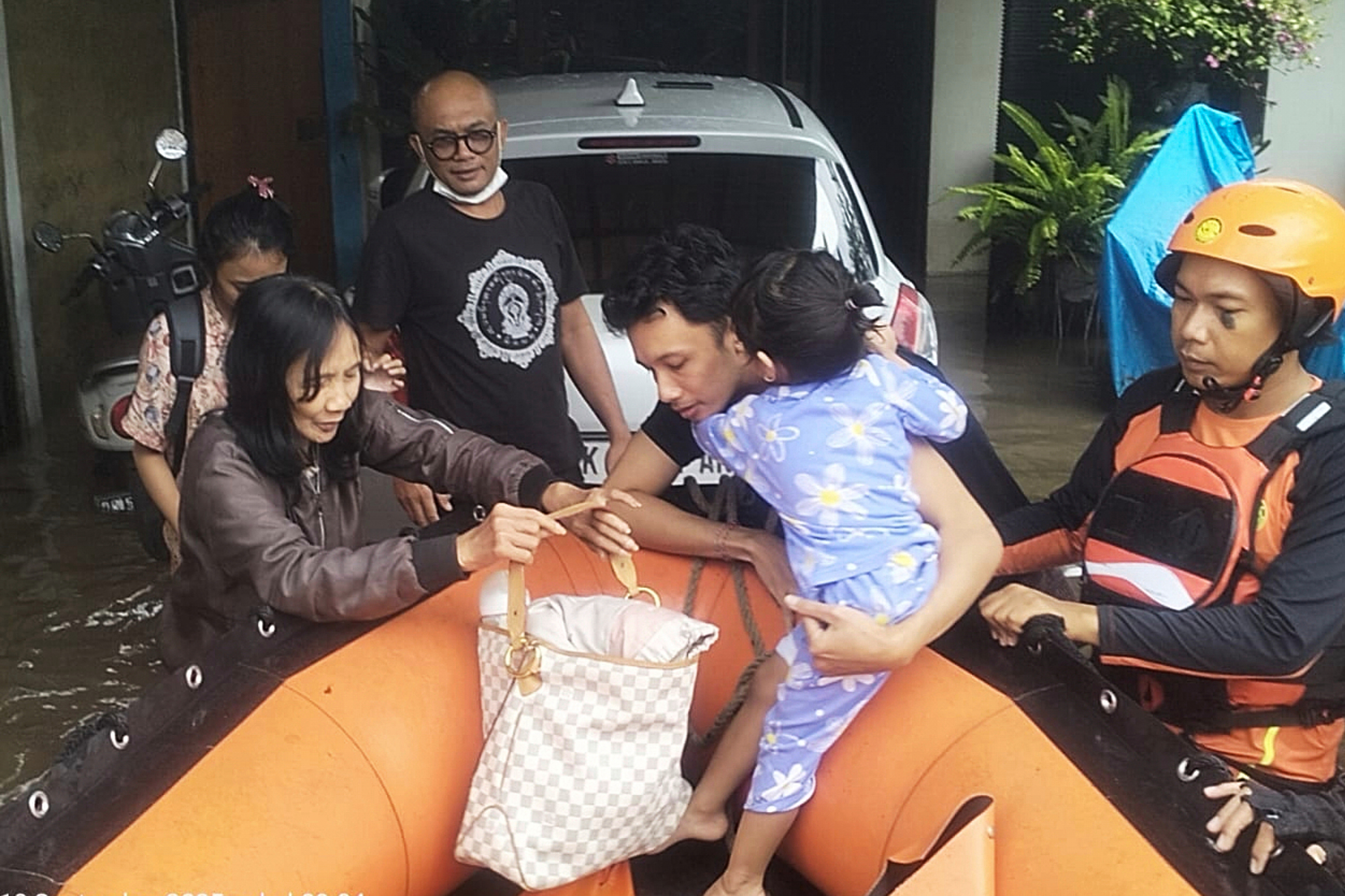 In this photo released by Indonesia's National Search and Rescue Agency (BASARNAS), rescuers evacuate residents from their flooded home in Denpasar, Bali, Indonesia  Wednesday, Sept. 10, 2025. (BASARNAS via AP)