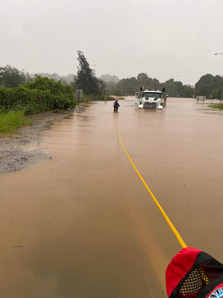 An SES worker secures himself to a rope as he enters floodwaters to inspect a trapped truck. 