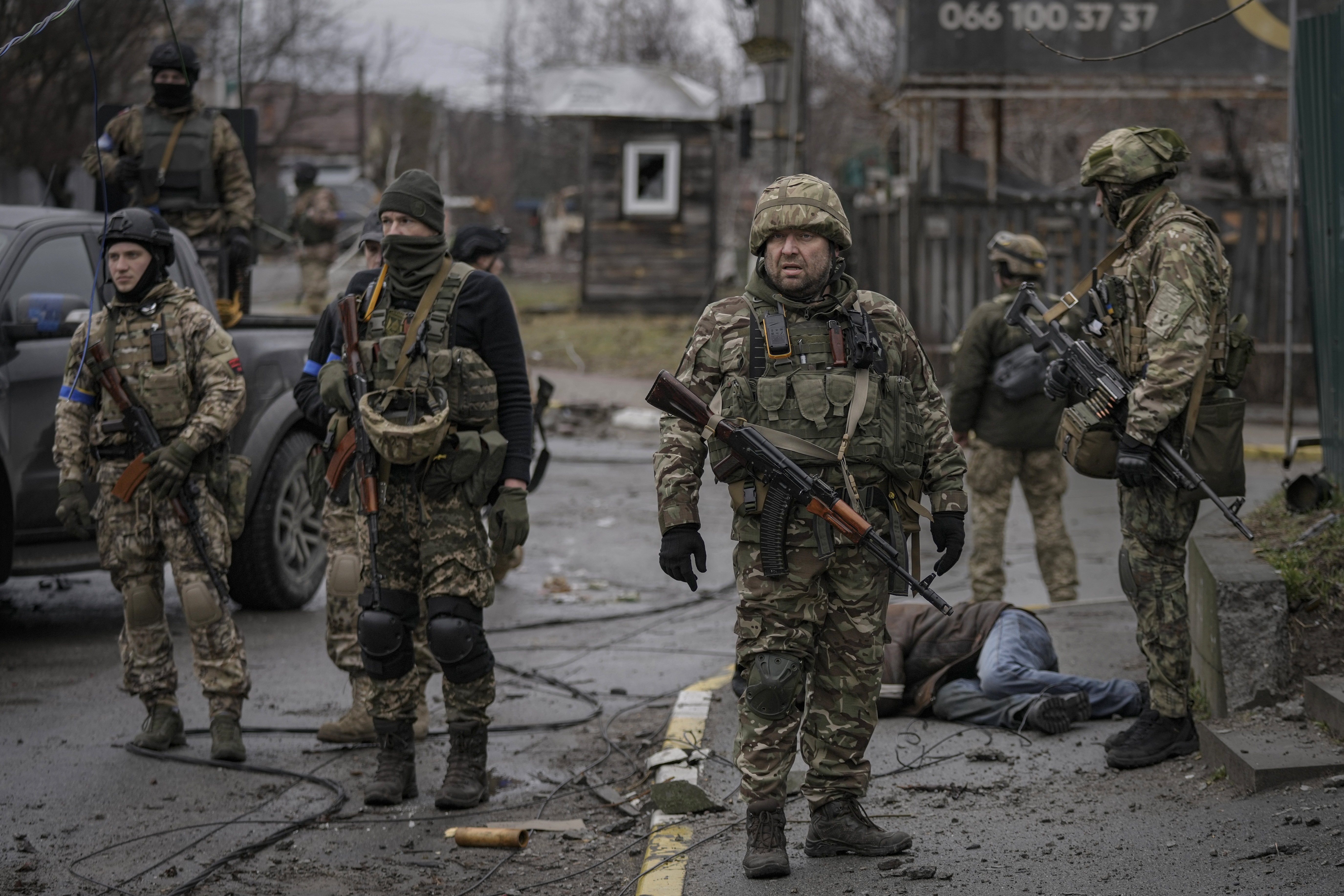 Ukrainian servicemen stand surrounding the body of man dressed in civilian clothing, in the formerly Russian-occupied Kyiv suburb of Bucha. 