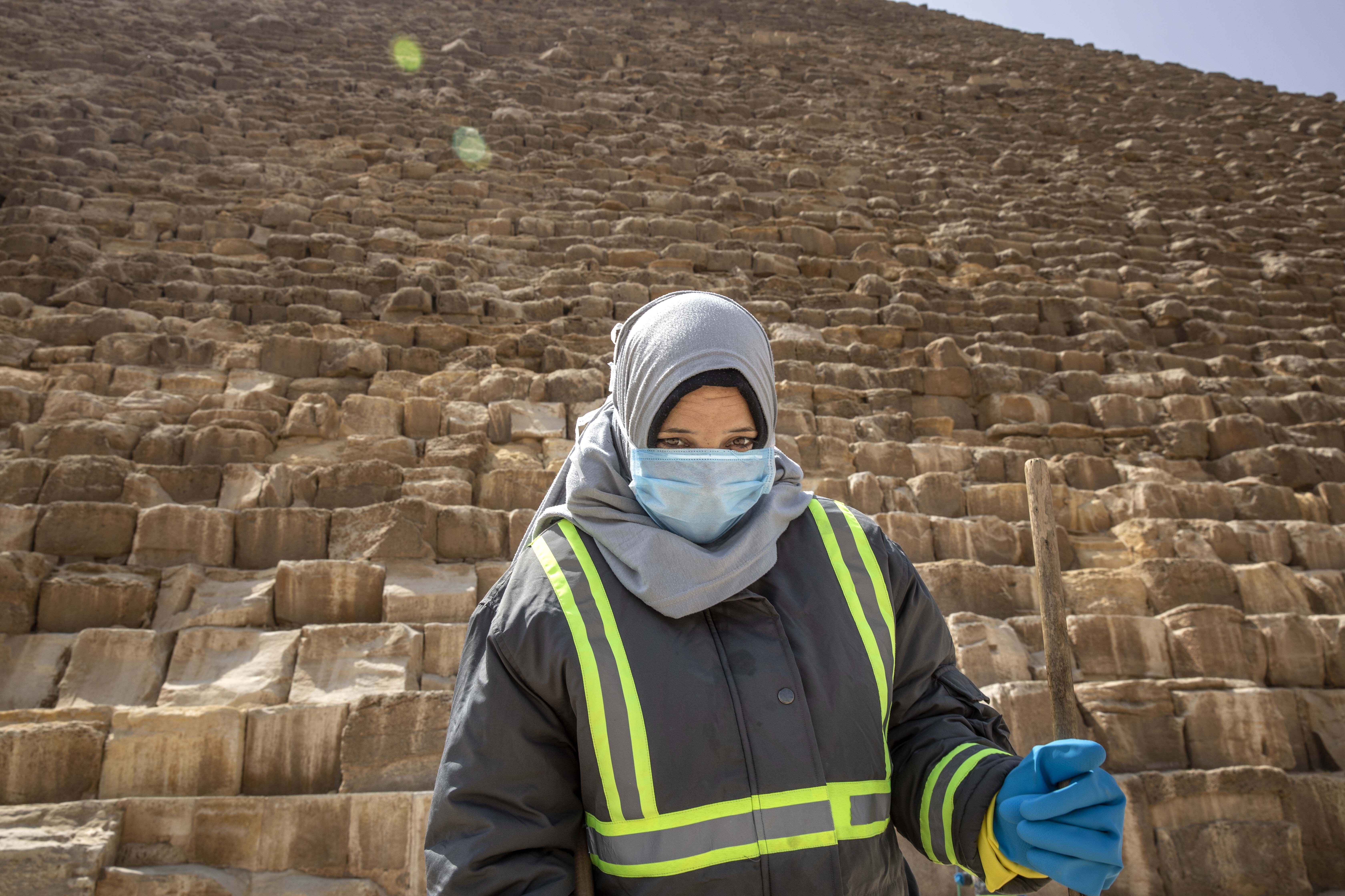 A municipal worker cleans at the Giza Pyramids as a prevention measure due to the coronavirus outbreak, in Giza,  Egypt, Wednesday, March 25, 2020. 