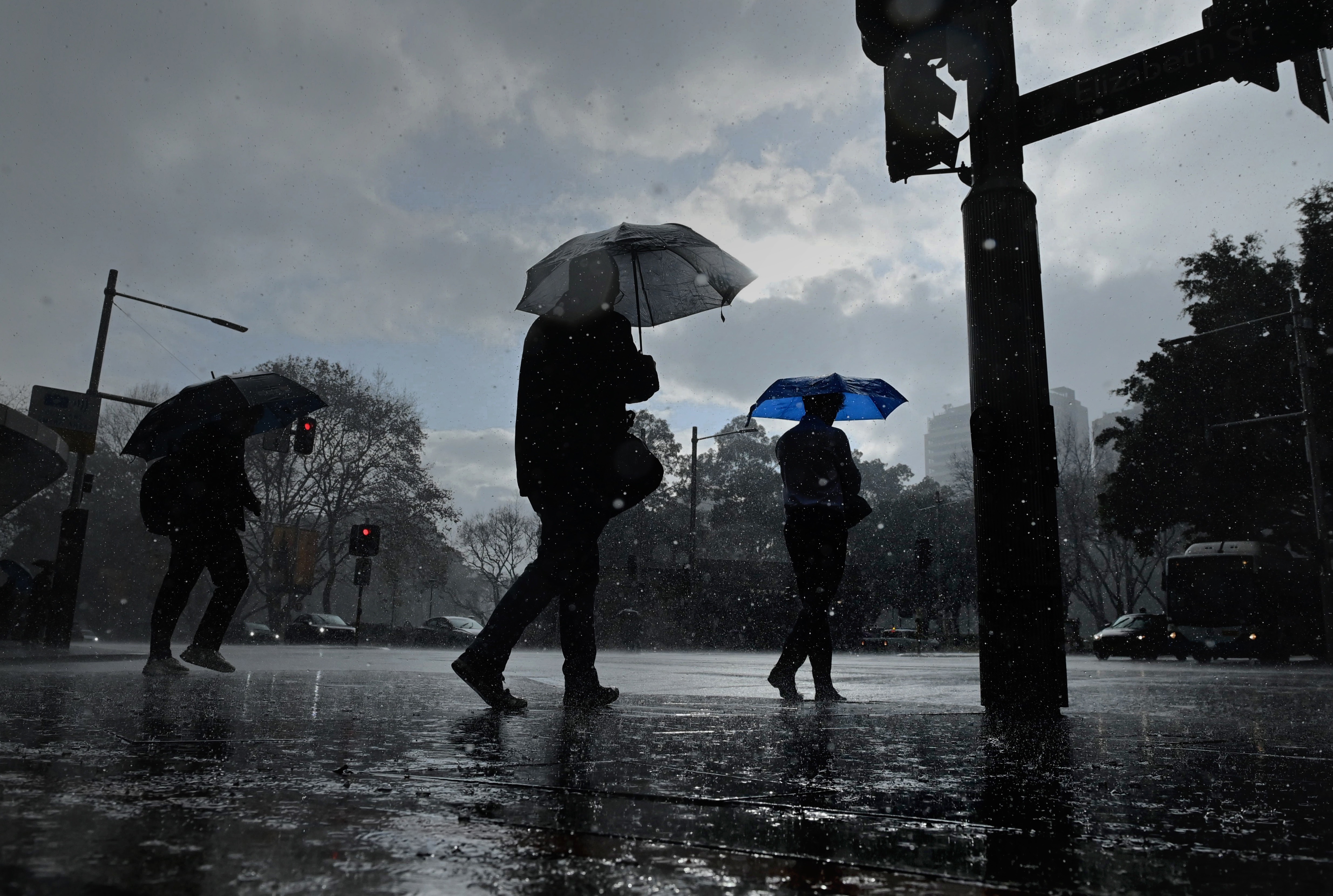 People protect themselves with umbrellas during a rain shower in the centre of Sydney