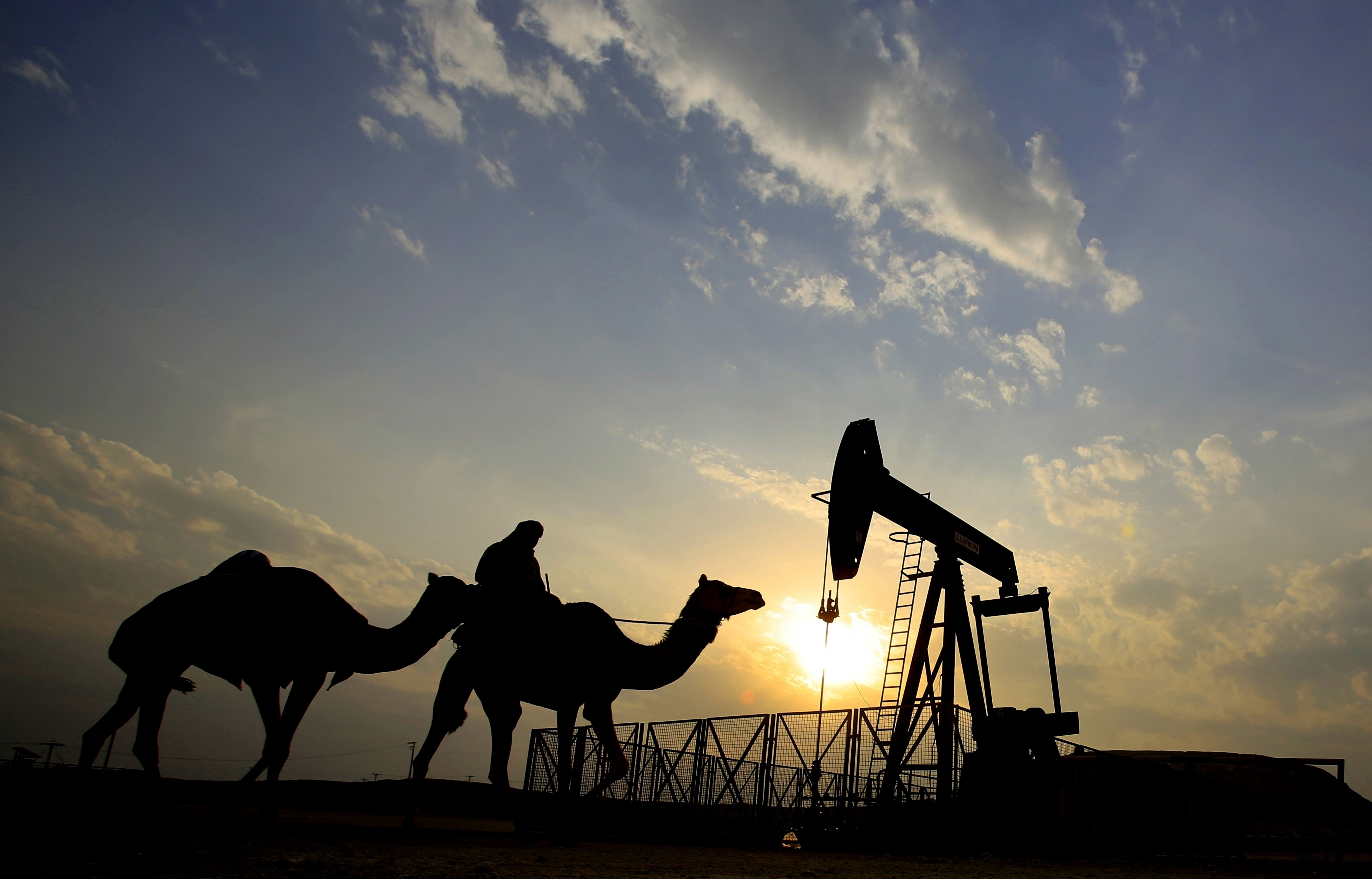 A man rides a camel through the desert oil field and winter camping area of Sakhir, Bahrain.