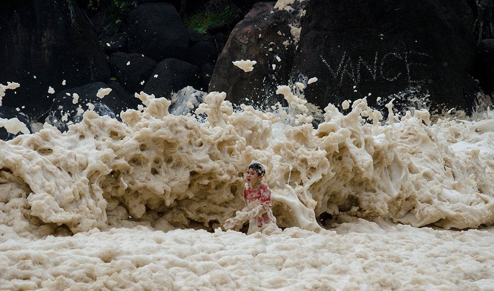 A child plays in the sea foam at Froggies Beach in Coolangatta following Cyclone Marcia in 2015.