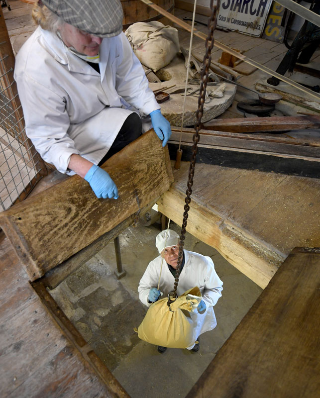 Millers Pete Loosmore and Imogen Bittner use a sack hoist to raise raw grain to the bin loft.