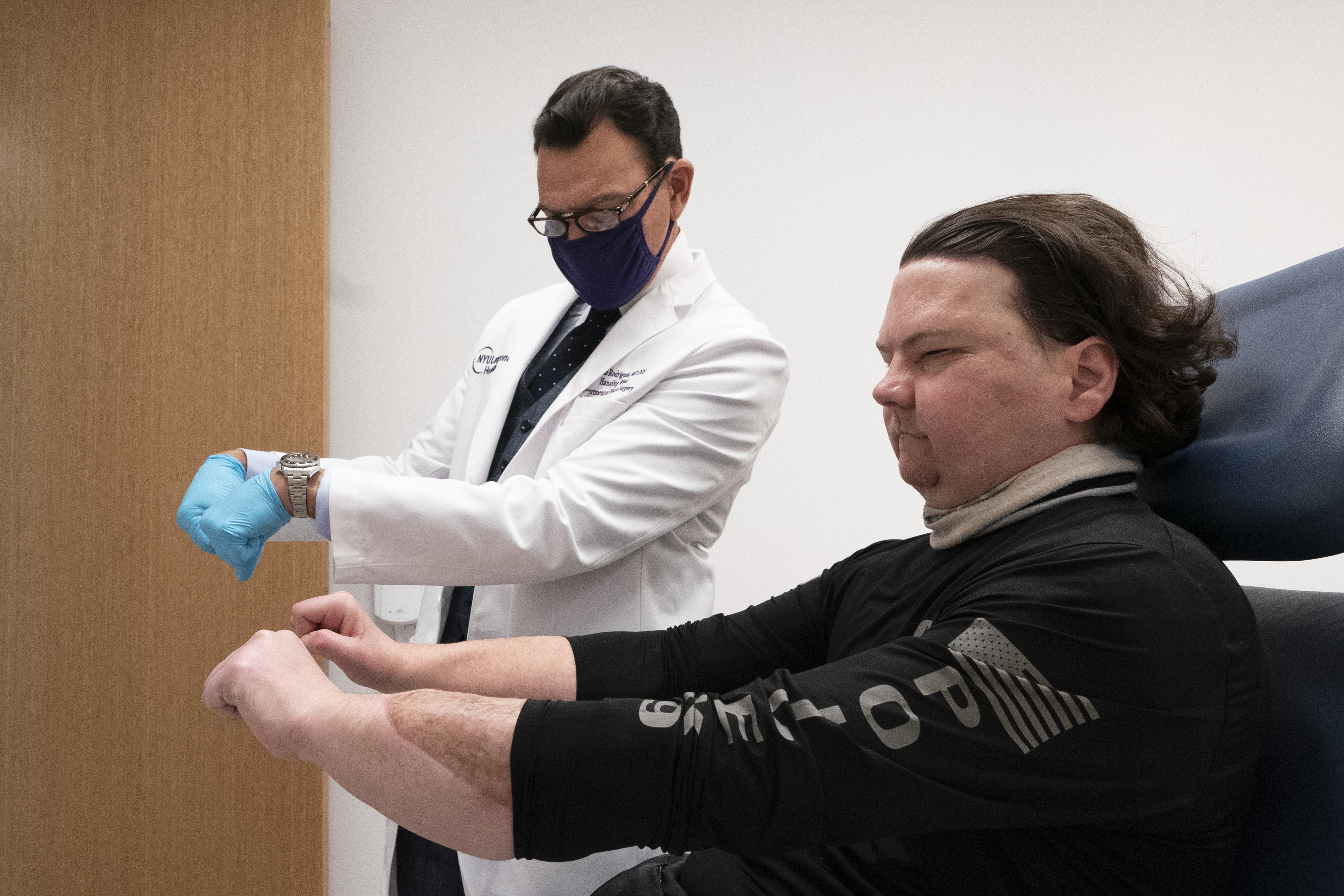 Dr Eduardo Rodriguez has Joe DiMeo demonstrate the flexibility in his new hands, Monday, Jan. 25, 2021 at NYU Langone Health in New York. (AP Photo/Mark Lennihan)