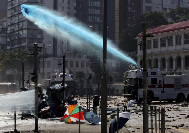 An armoured police vehicle sprays blue-dyed liquid during a confrontation with protesters at the Hong Kong Polytechnic University in Hong Kong. A Hong Kong police officer was hit in the leg by an arrow as authorities used tear gas and water cannons to try to drive back protesters occupying a university campus and surrounding streets