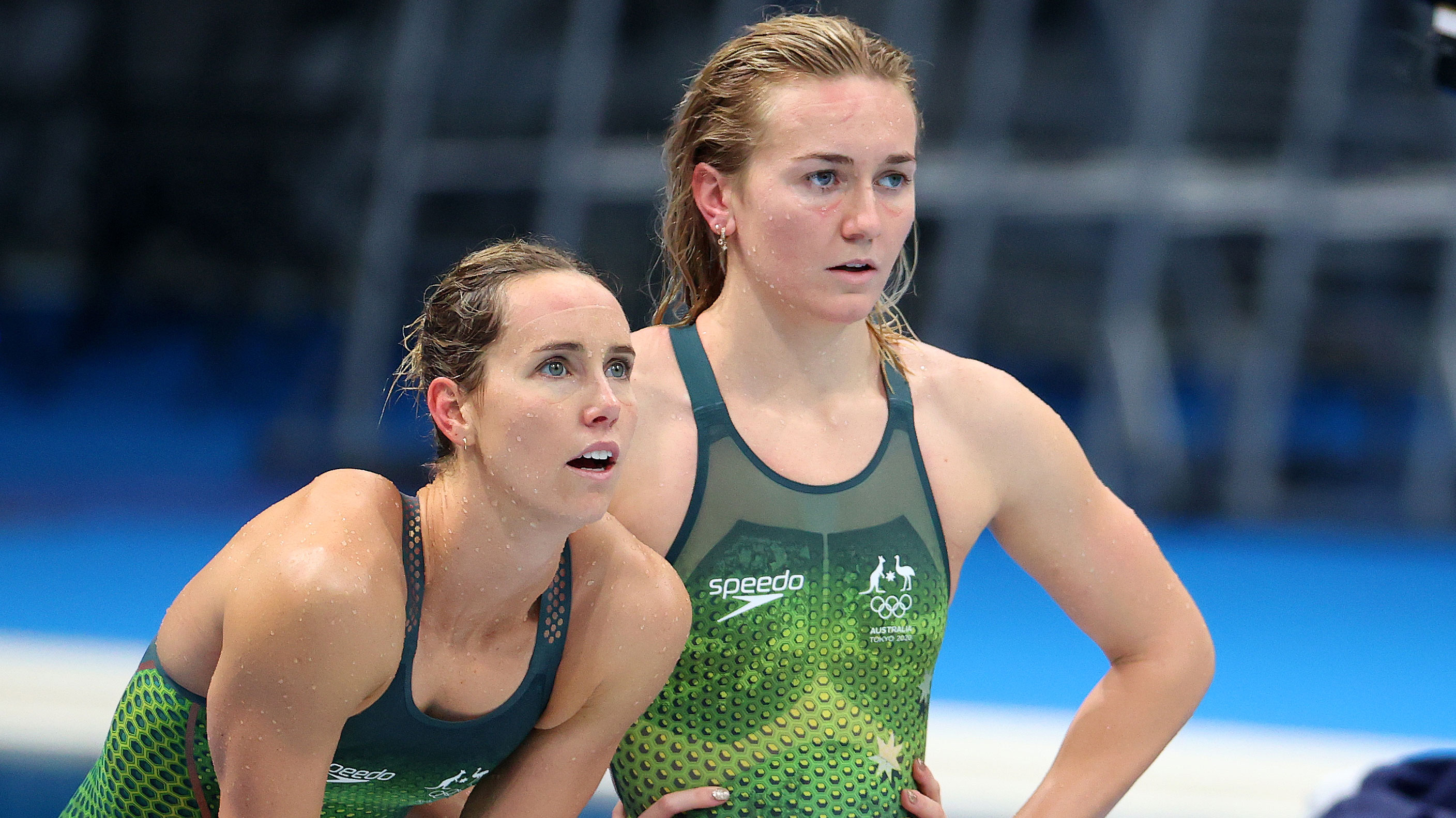 Emma McKeon and Ariarne Titmus look on in shock.