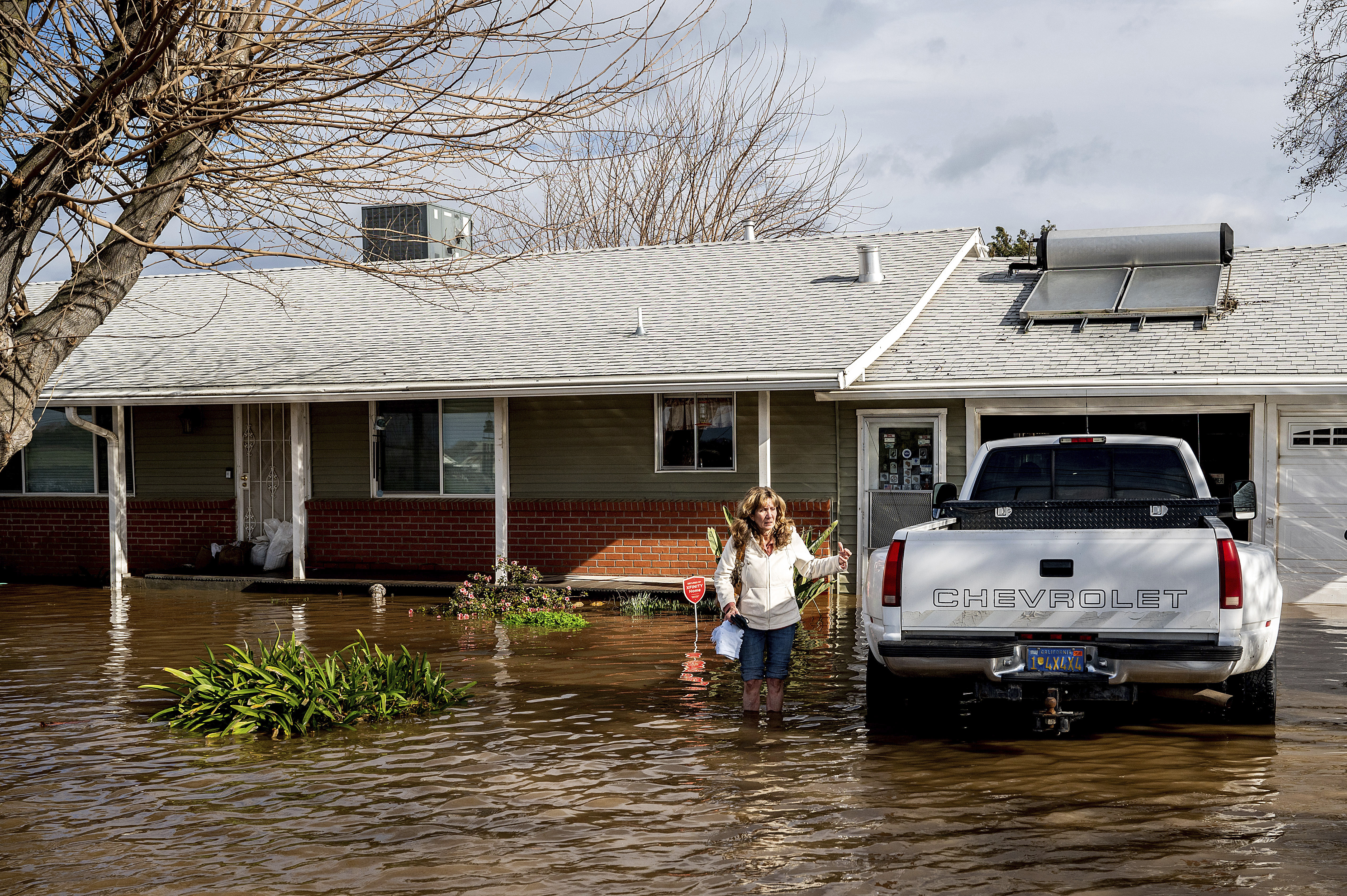 Kim Ochoa leaves her Merced, Calif., home, which is surrounded by floodwaters, as storms continue to batter the state on Tuesday, Jan. 10, 2023