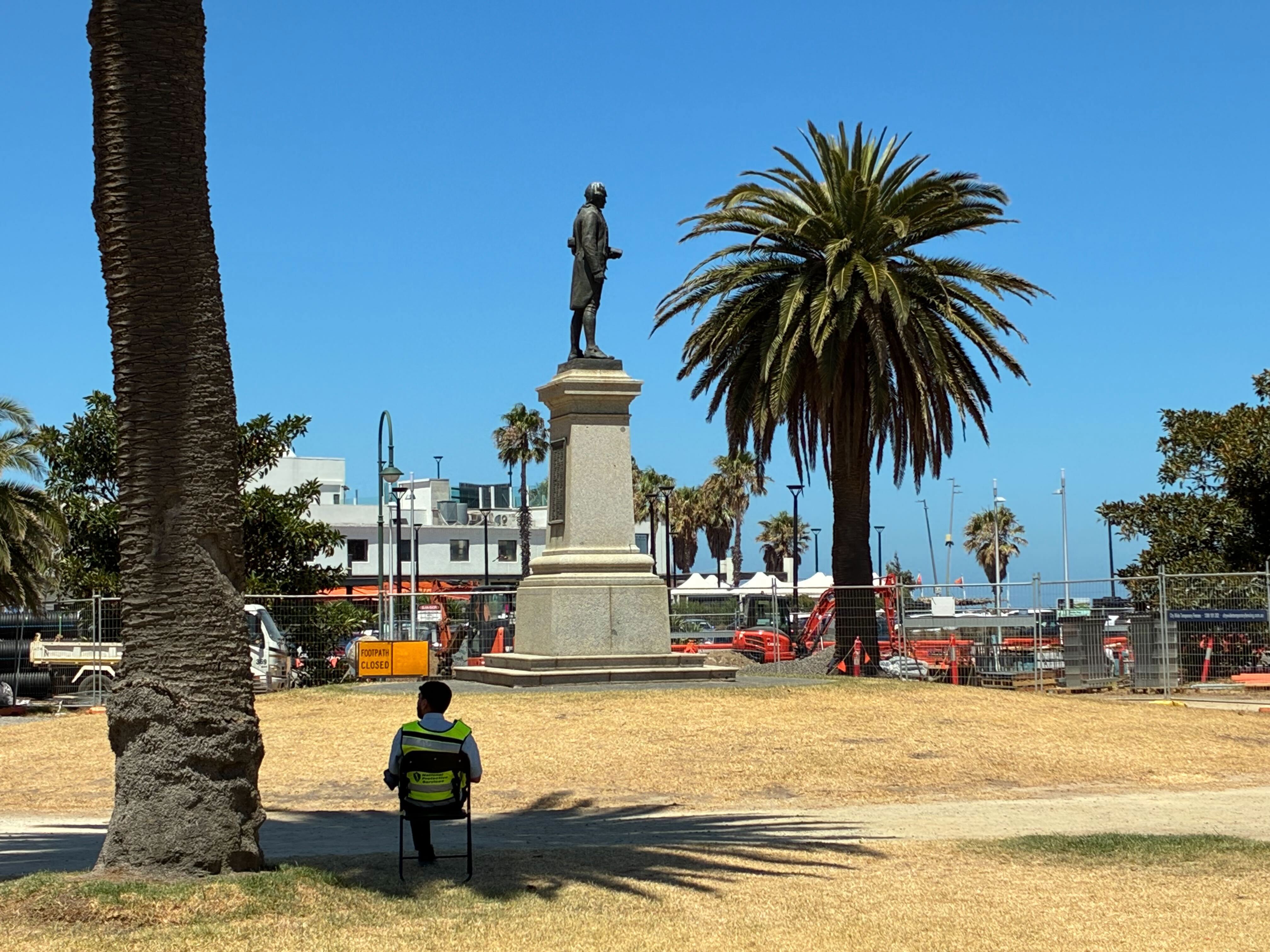 A security guard watches over a memorial to Captain James Cook in St Kilda on Australia Day after it was toppled by vandals two years ago. 26th January, 2026. Photo Rachael Ward.