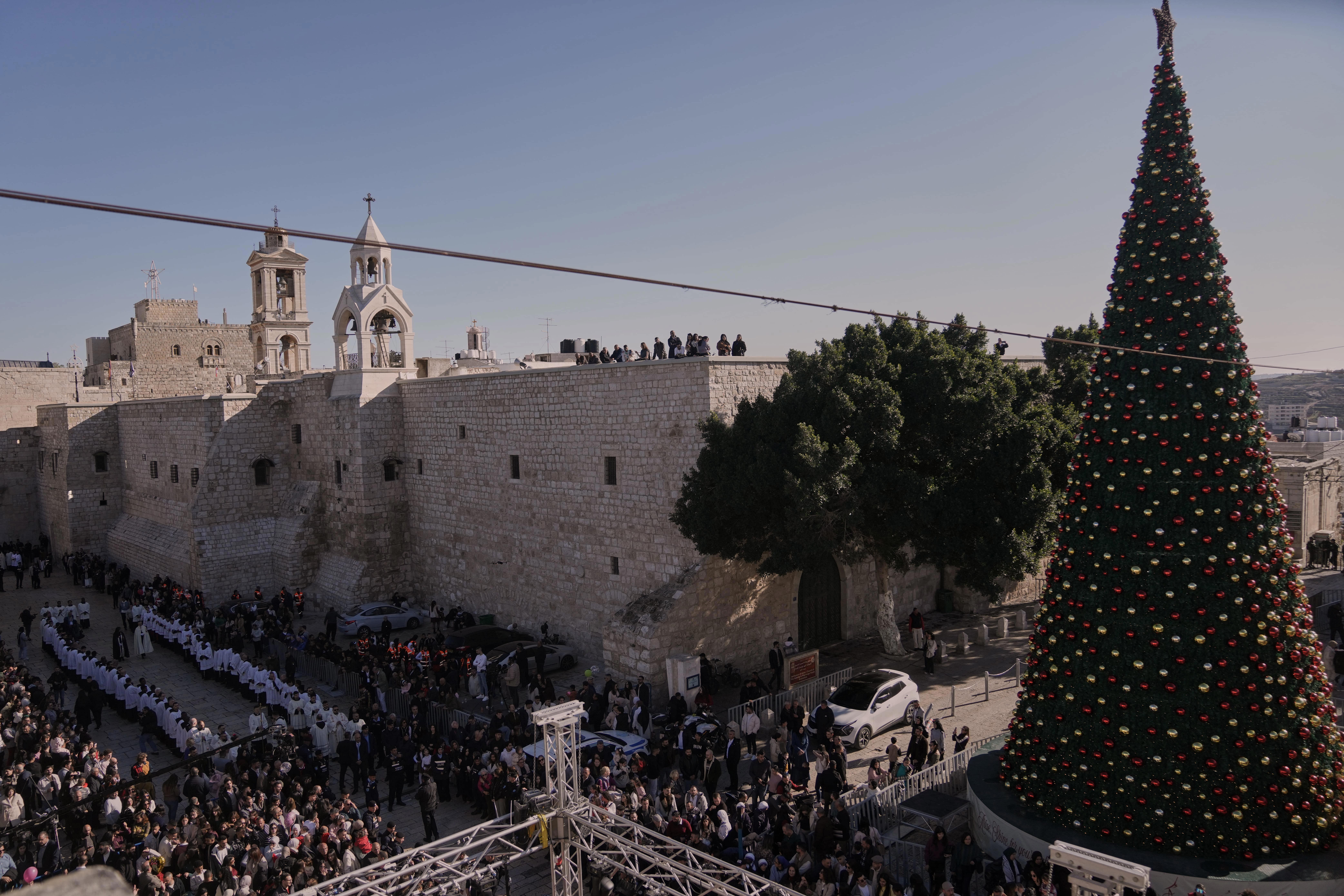Catholic clergy walk in procession next to the Church of the Nativity