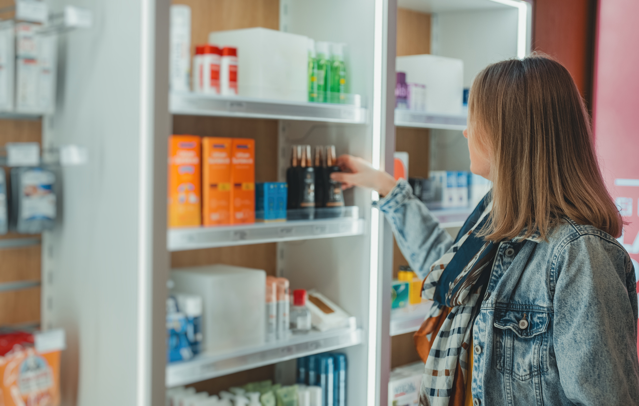 Woman chooses a cream at a pharmacy.
