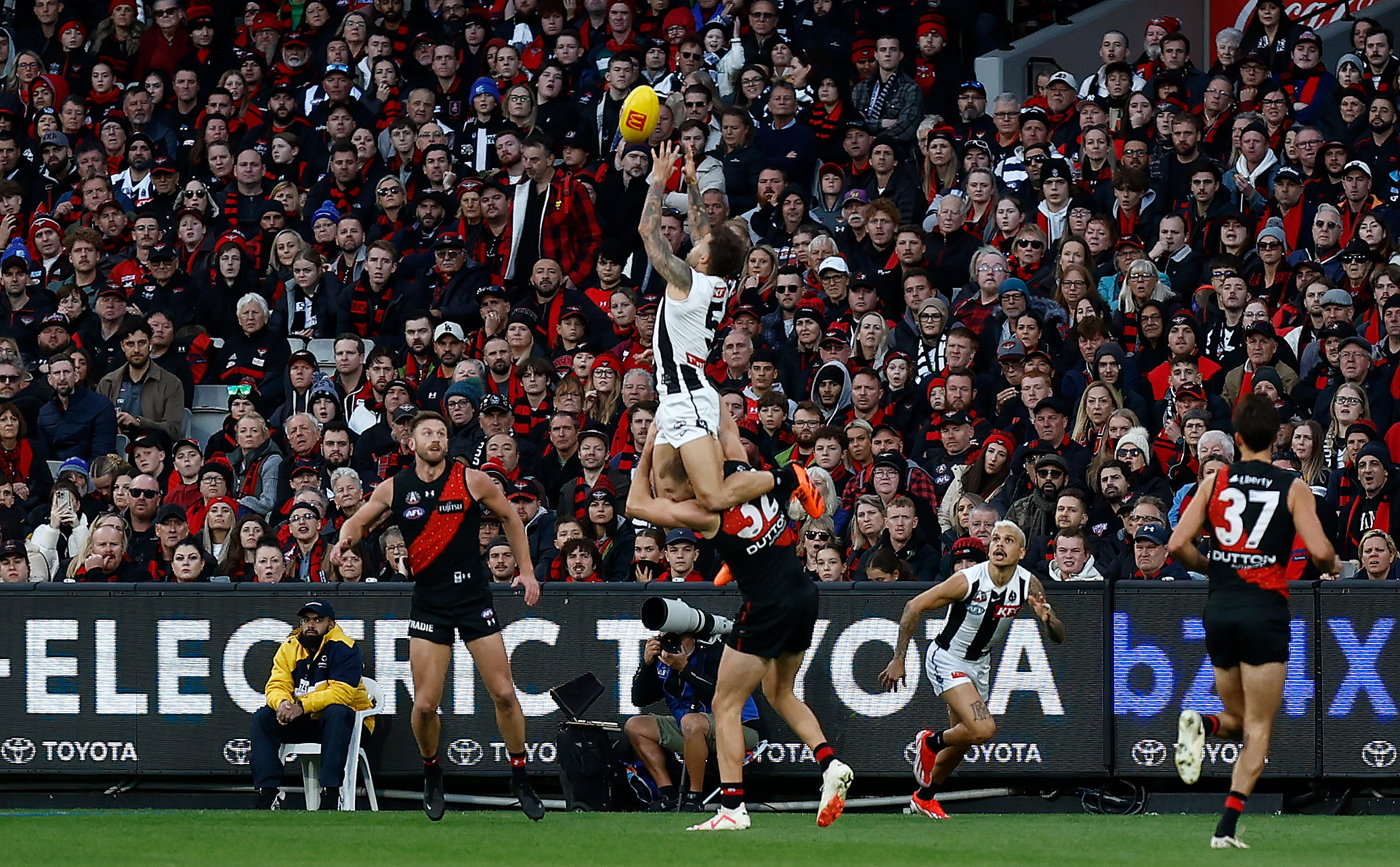 Jamie Elliott of the Magpies takes a spectacular mark over Ben McKay of the Bombers during the annual Anzac Day clash.