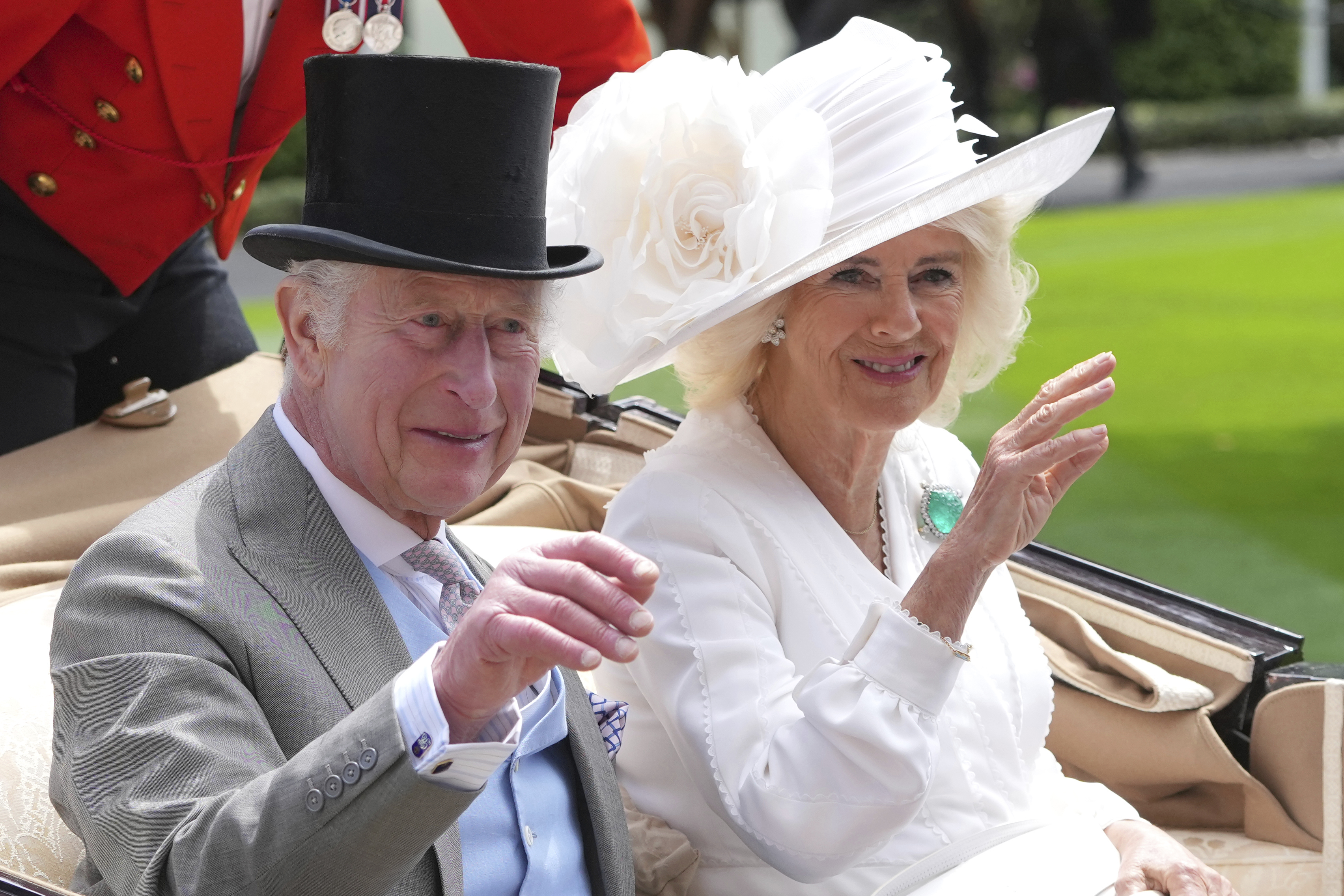 Britain's King Charles III and Queen Camilla wave to the crowds as they arrive by carriage in the parade ring on the third day of the Royal Ascot, horse race meeting, traditional known as Ladies Day, at Ascot, England, Thursday, June 20, 2024. (AP Photo/Kin Cheung)