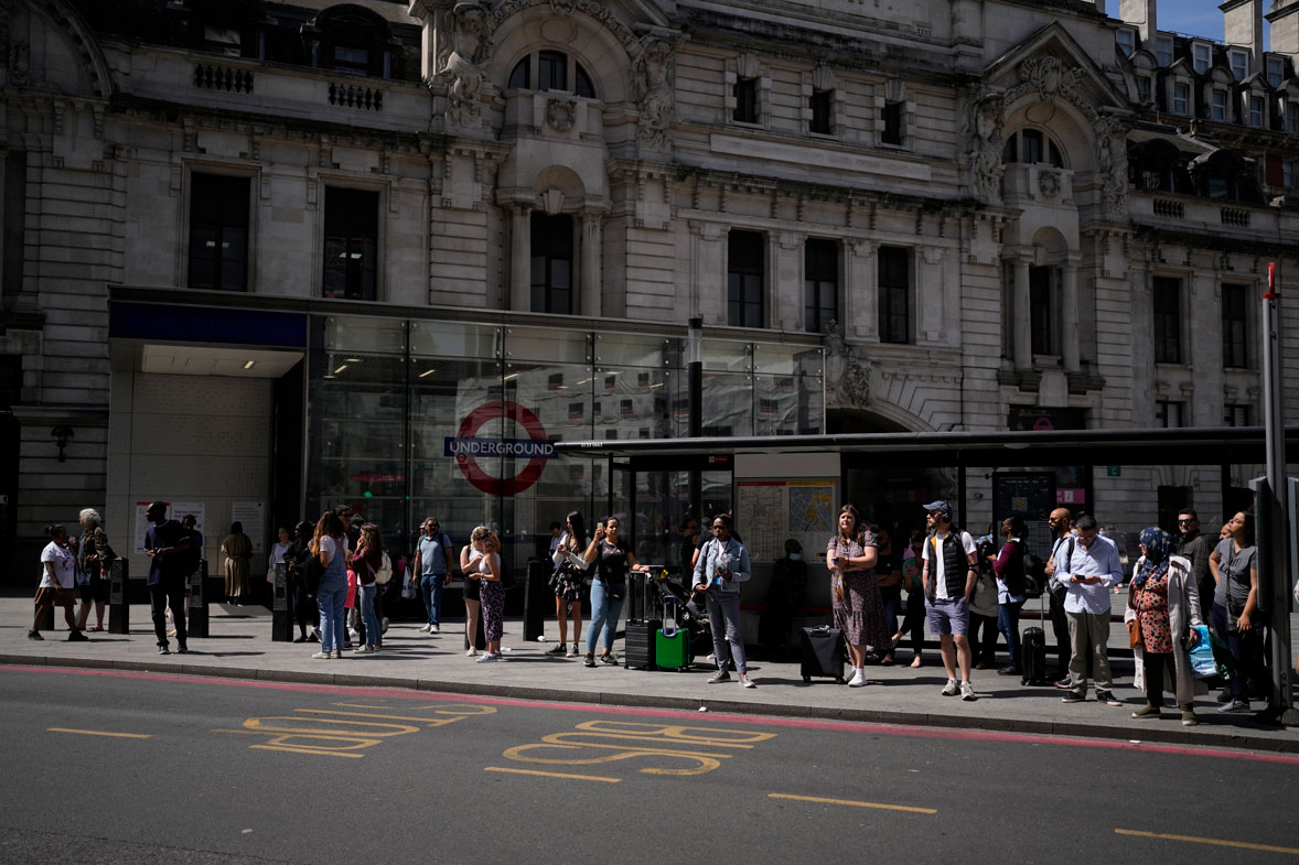 People wait to catch buses from a bus stop outside Victoria railway station, in London, during a railway and underground train workers strike, Tuesday, June 21, 2022. 