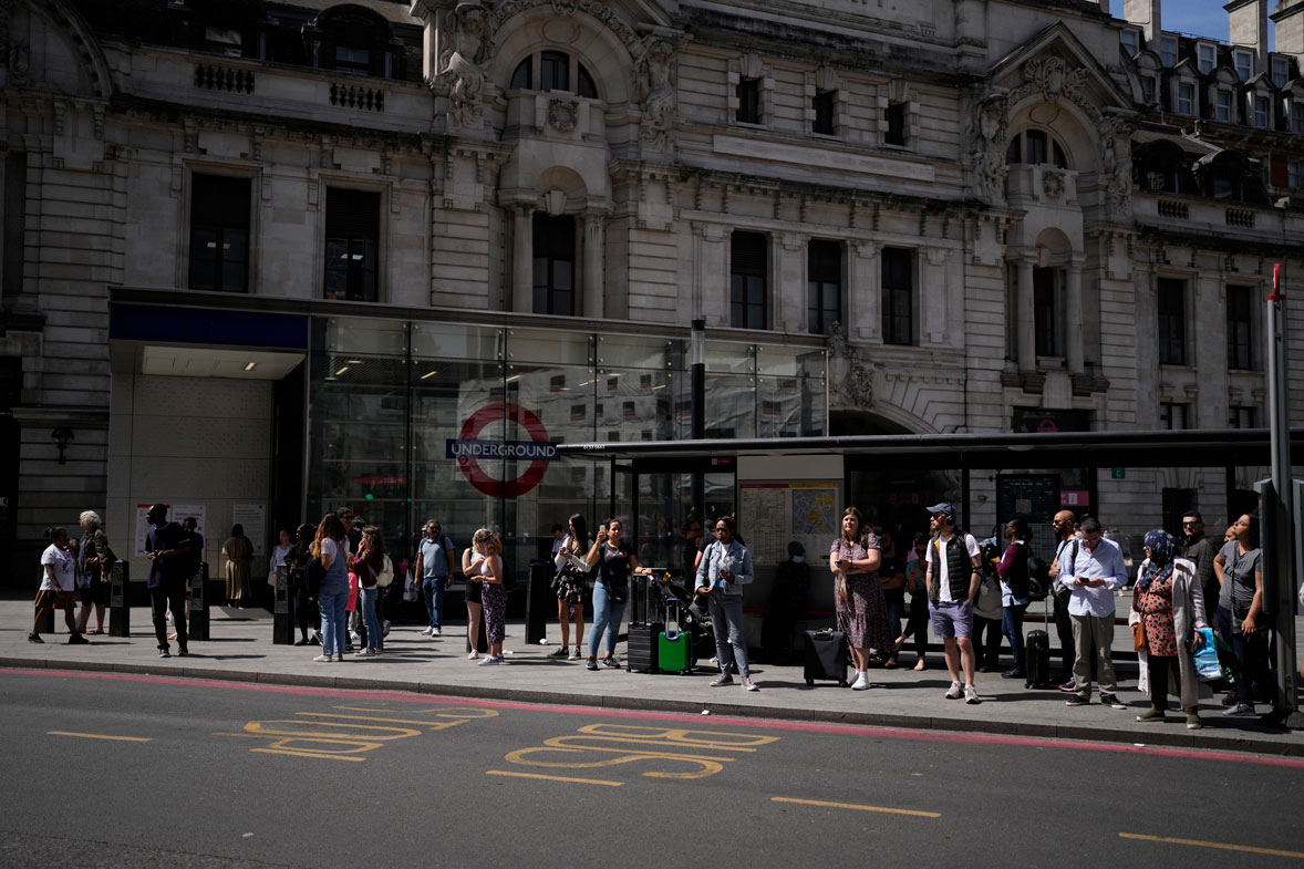 People wait to catch buses from a bus stop outside Victoria railway station, in London, during a railway and underground train workers strike, Tuesday, June 21, 2022.
