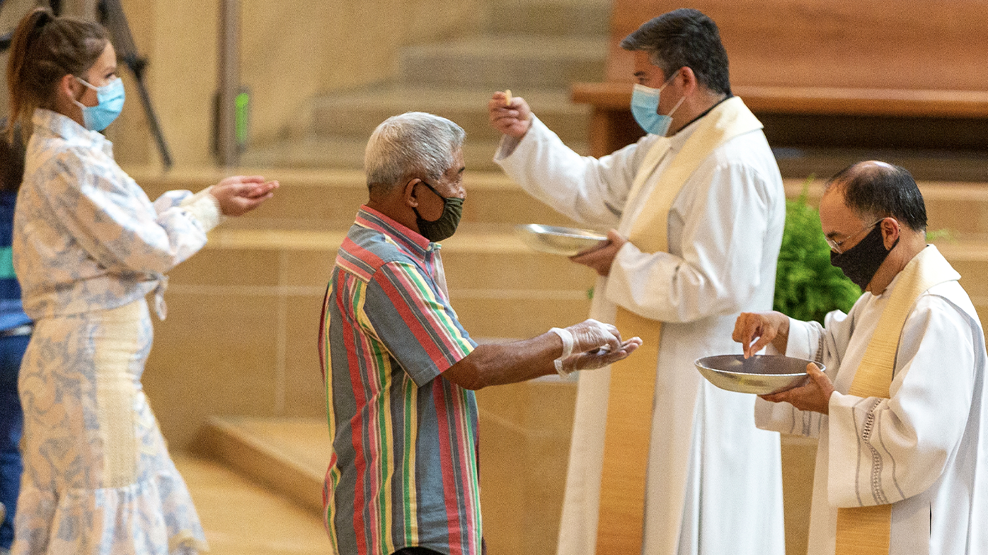 The faithful wear masks and some wear gloves as they receive Communion at the first English Mass with faithful present at the Cathedral of Our Lady of the Angels in downtown Los Angeles, Sunday, June 7, 2020. 