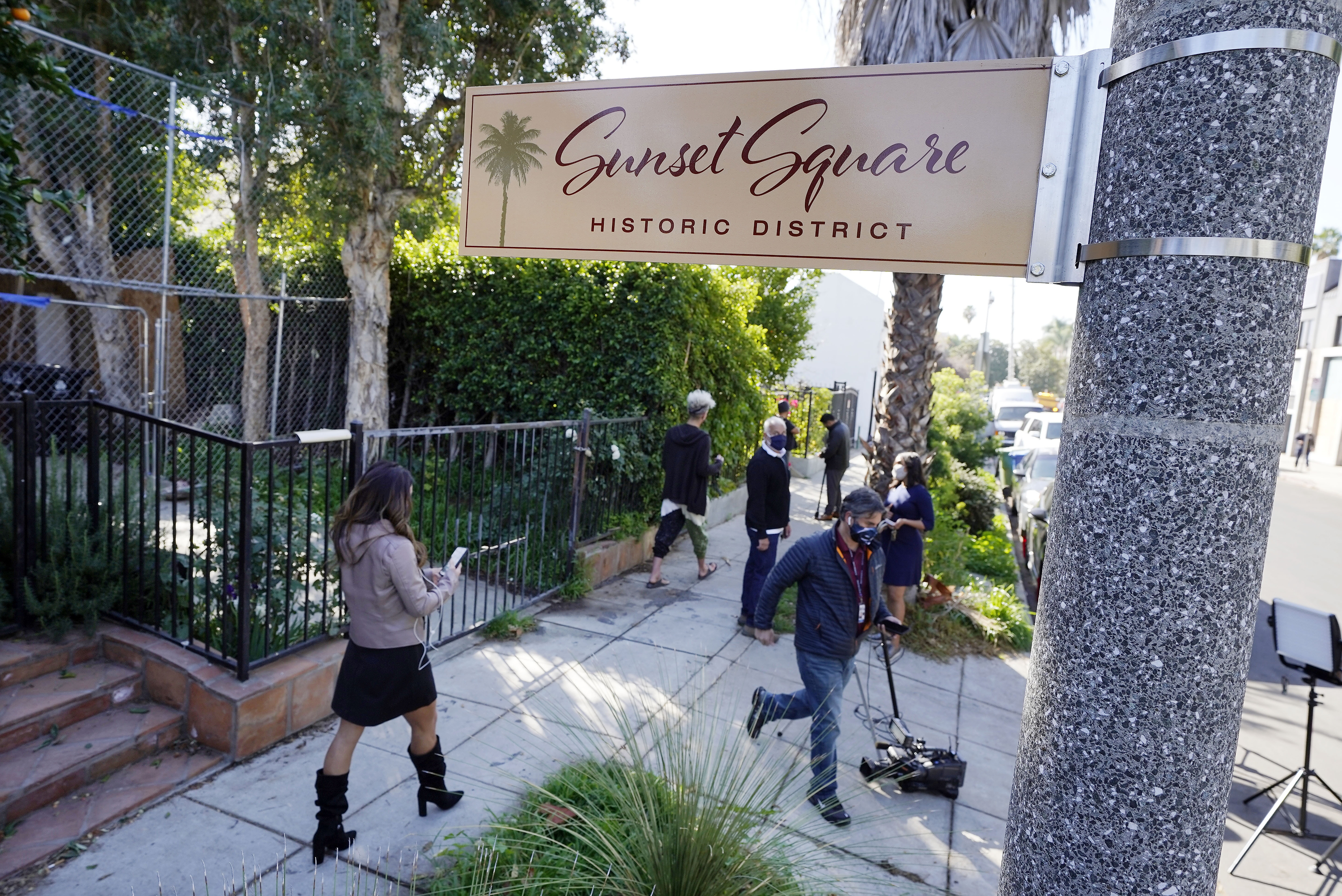 Miembros de los medios de comunicación y vecinos caminan cerca de un área en North Sierra Bonita Avenue donde le dispararon al paseador de perros de Lady Gaga y le robaron dos de sus bulldogs franceses en Los Ángeles el 25 de febrero de 2021. 