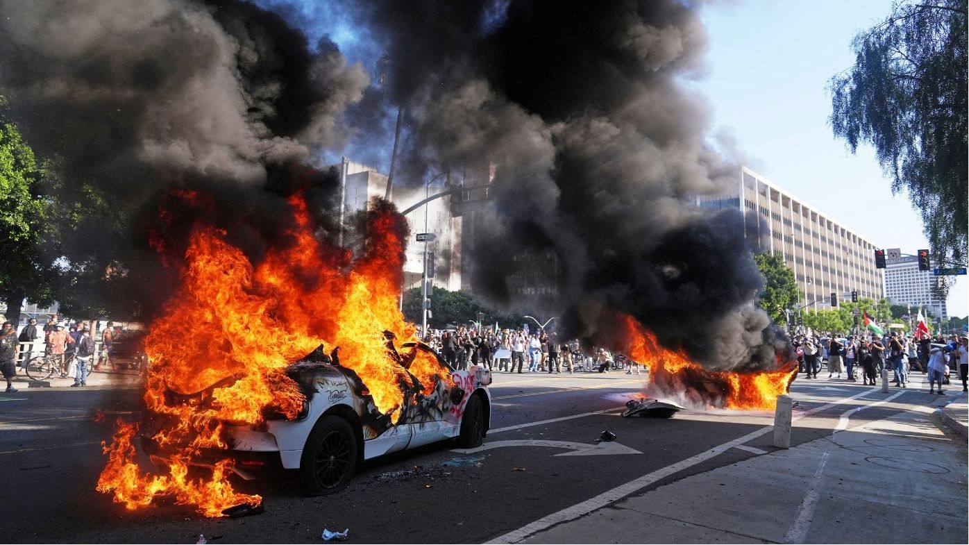 Two Waymo taxis burn near the metropolitan detention center of downtown Los Angeles, Sunday, June 8, 2025, following last night's immigration raid protest. (AP Photo/Jae C. Hong)