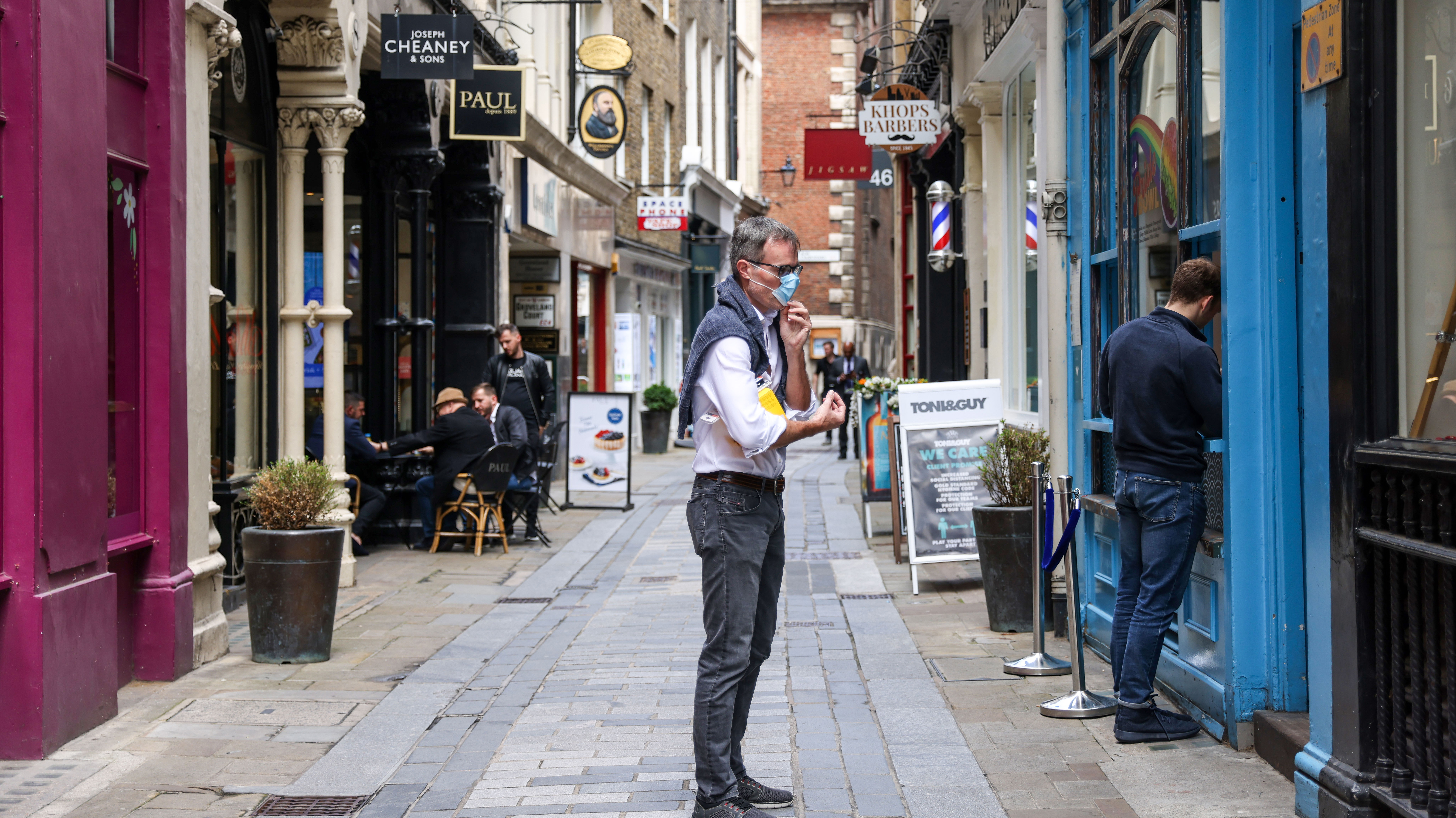 A pedestrian adjusts his mask before entering a takeaway restaurant on Bow Lane in London