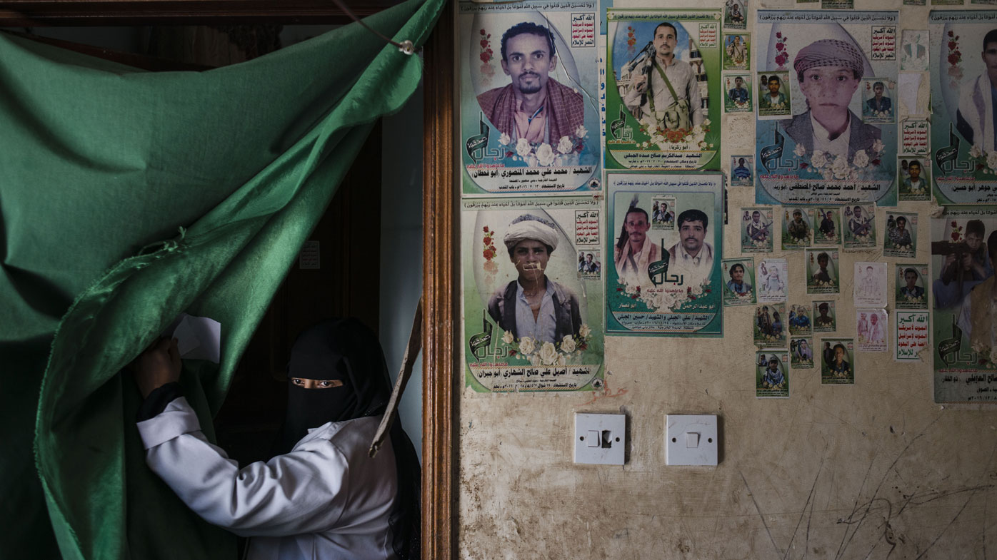 A face stares from behind a makeshift curtain, scenes from Yemen.
