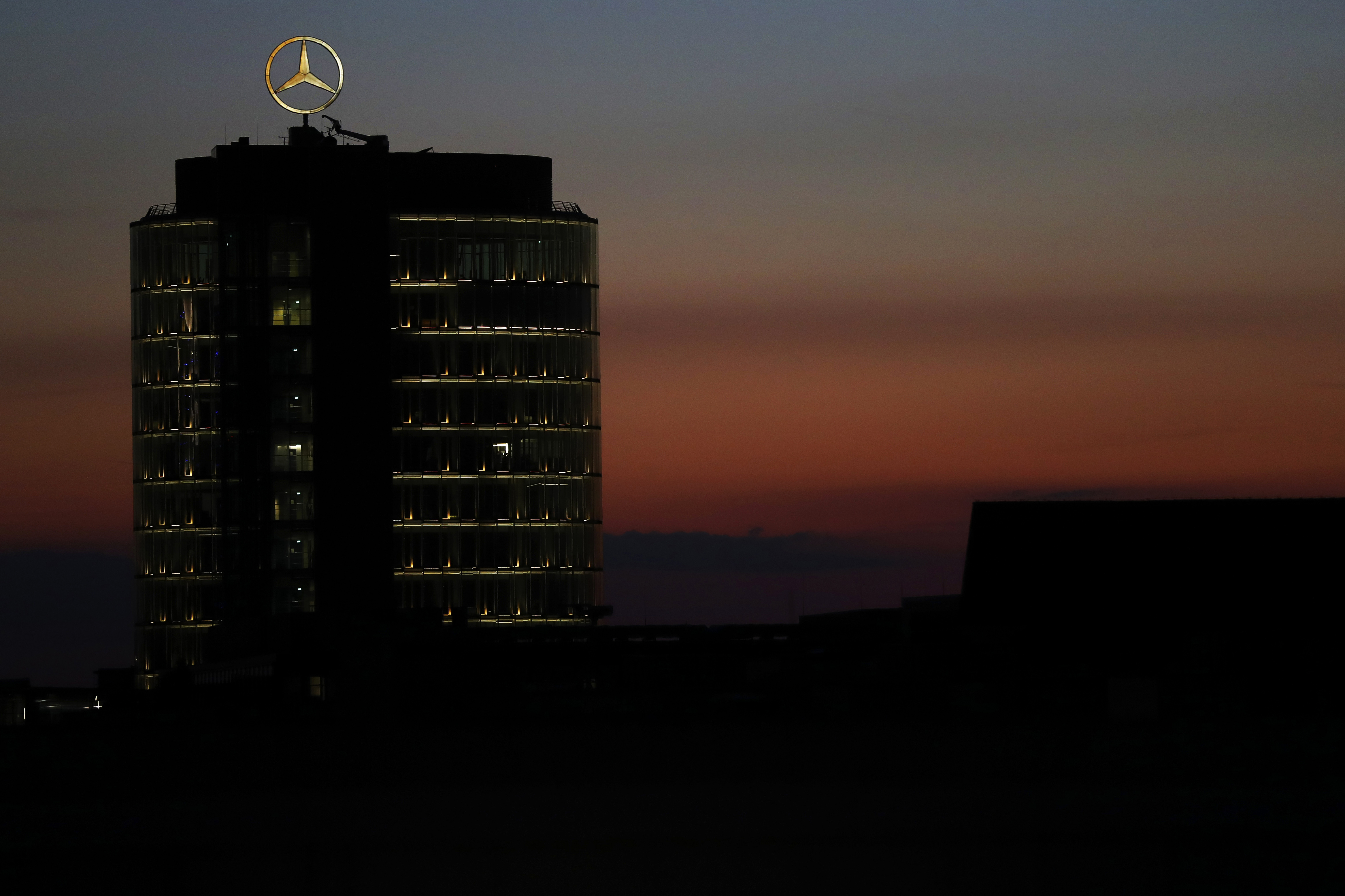 The sun sets behind the logo of German car maker Mercedes Benz in Munich, Germany, Wednesday, July 29, 2020. (AP Photo/Matthias Schrader)Alt