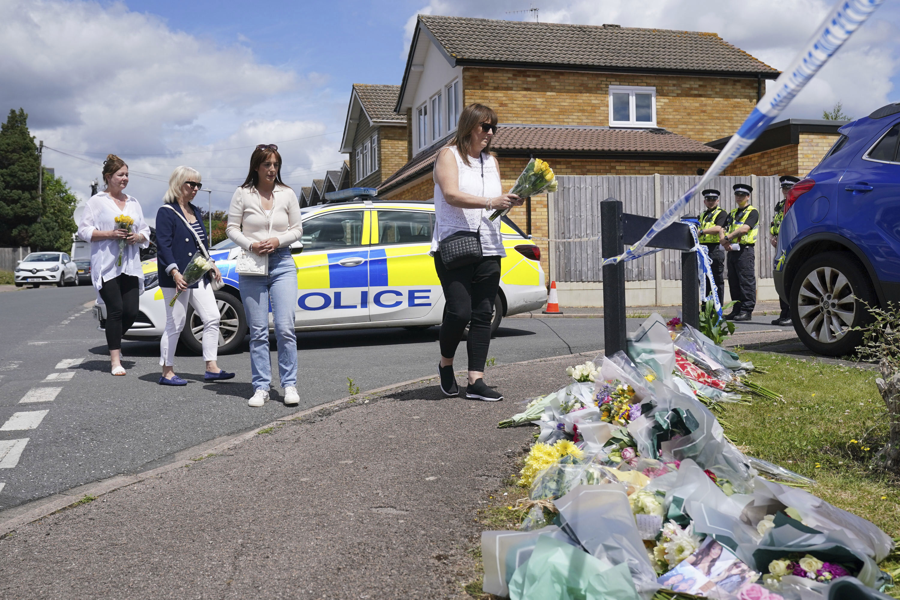 Family friend Lea Holloway, left, arrives with others to place tributes following the deaths of three women who were killed in an attack at their home, on Tuesday in Bushey, England, Thursday July 11, 2024. 