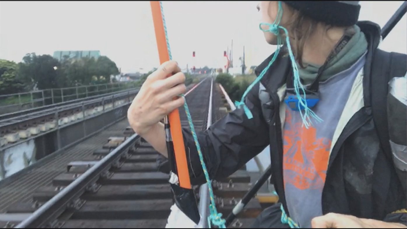 A climate change protester has suspended himself from a rail bridge in Sydney.