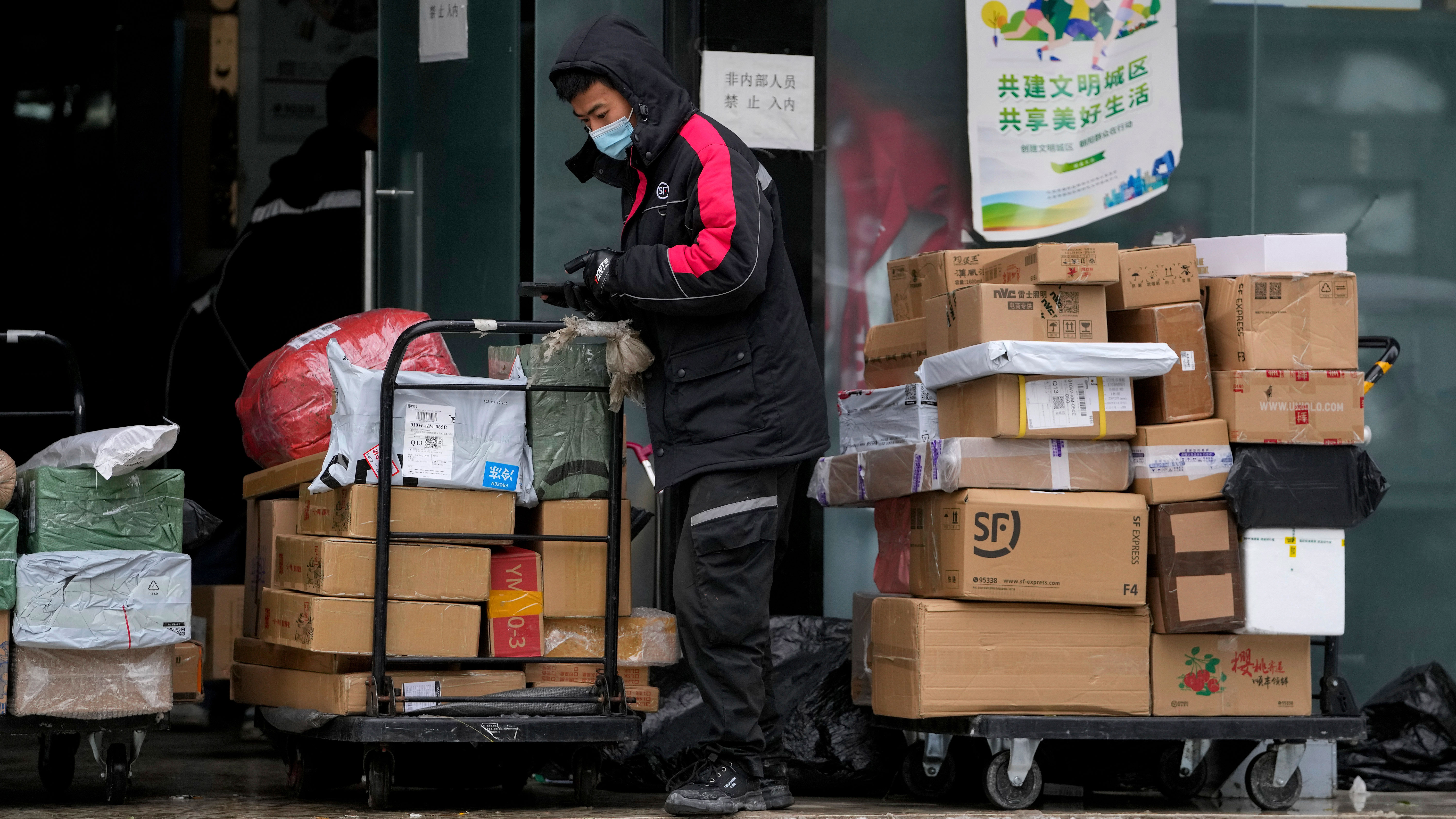 A worker of a private delivery company, wearing a face mask, sorts out parcels at its distribution center in Beijing.
