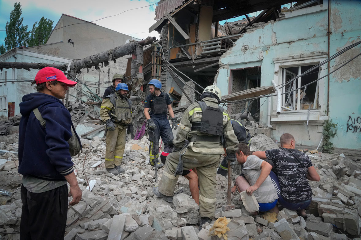 Search and rescue workers and local residents remove a body from under the rubble of a building after a Russian air raid in Lysychansk, Luhansk region, Ukraine, Thursday, June 16, 2022.