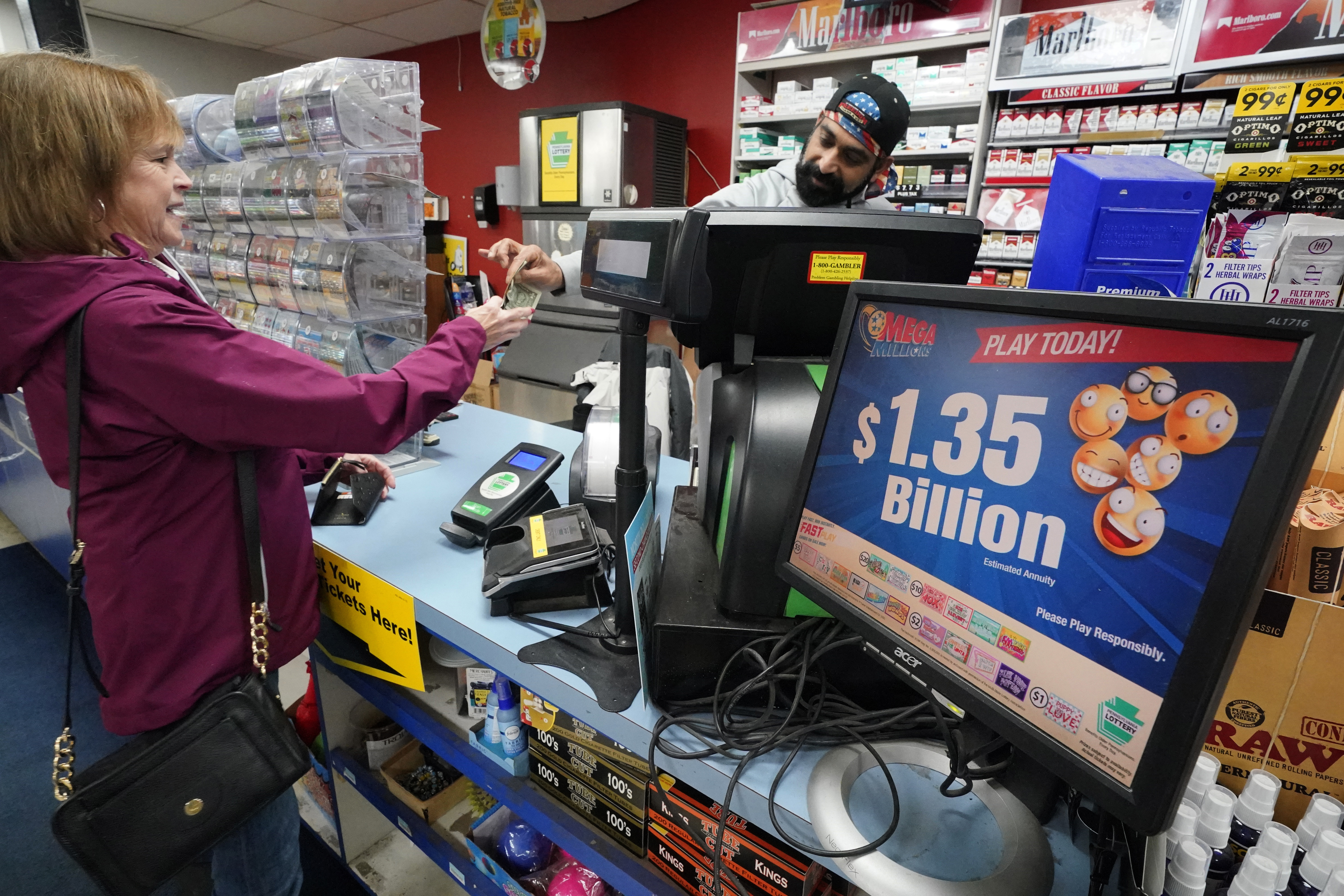 Un letrero de Mega Millions muestra el premio mayor estimado de $1,350 millones cuando un cliente compra un boleto de Mega Millions en el Cranberry Super Mini Mart en Cranberry, Pensilvania, el jueves 12 de enero de 2023. 