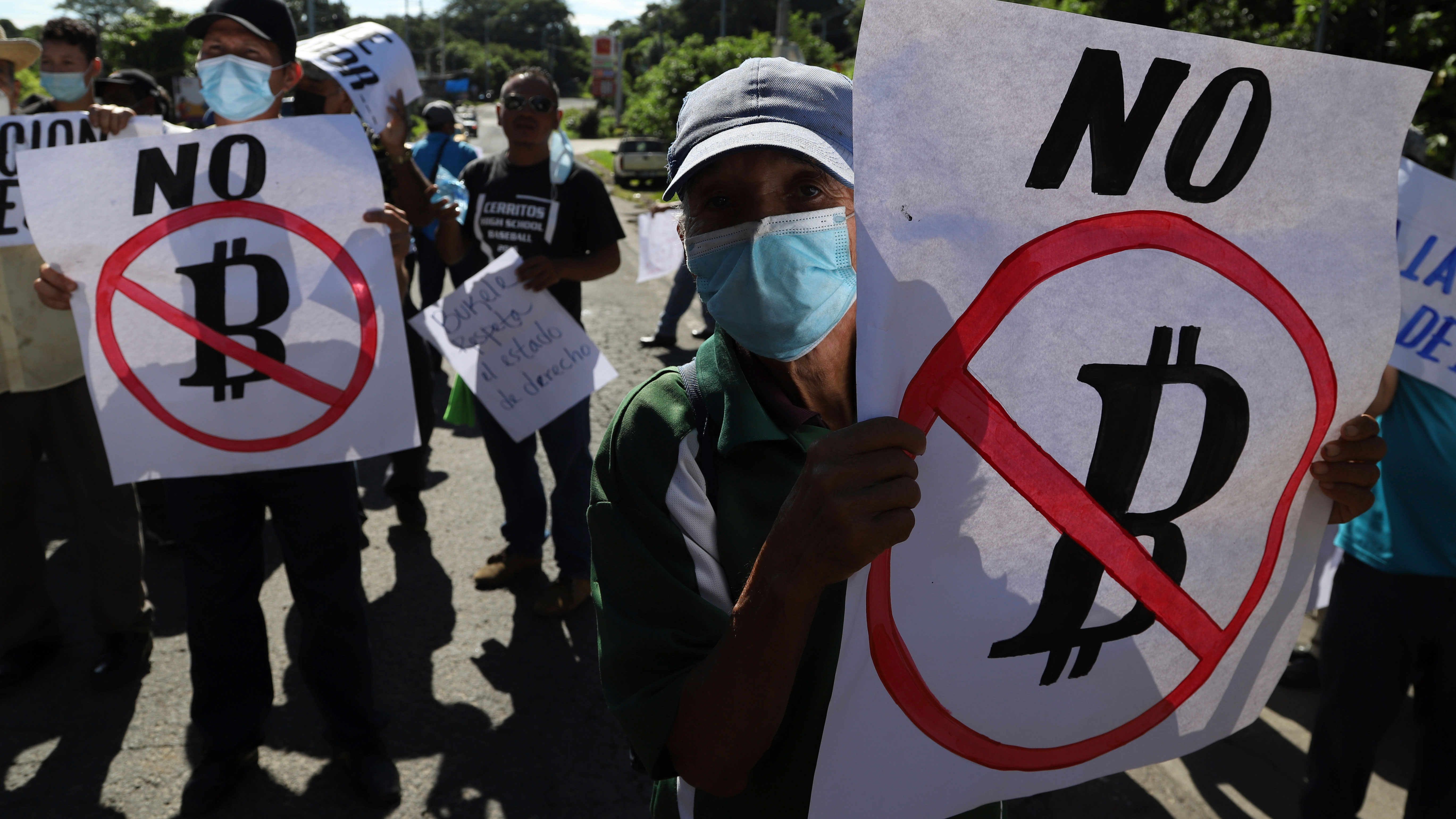 Farmers hold signs emblazoned with messages against the country adopting Bitcoin as legal tender, during a protest in El Salvador.