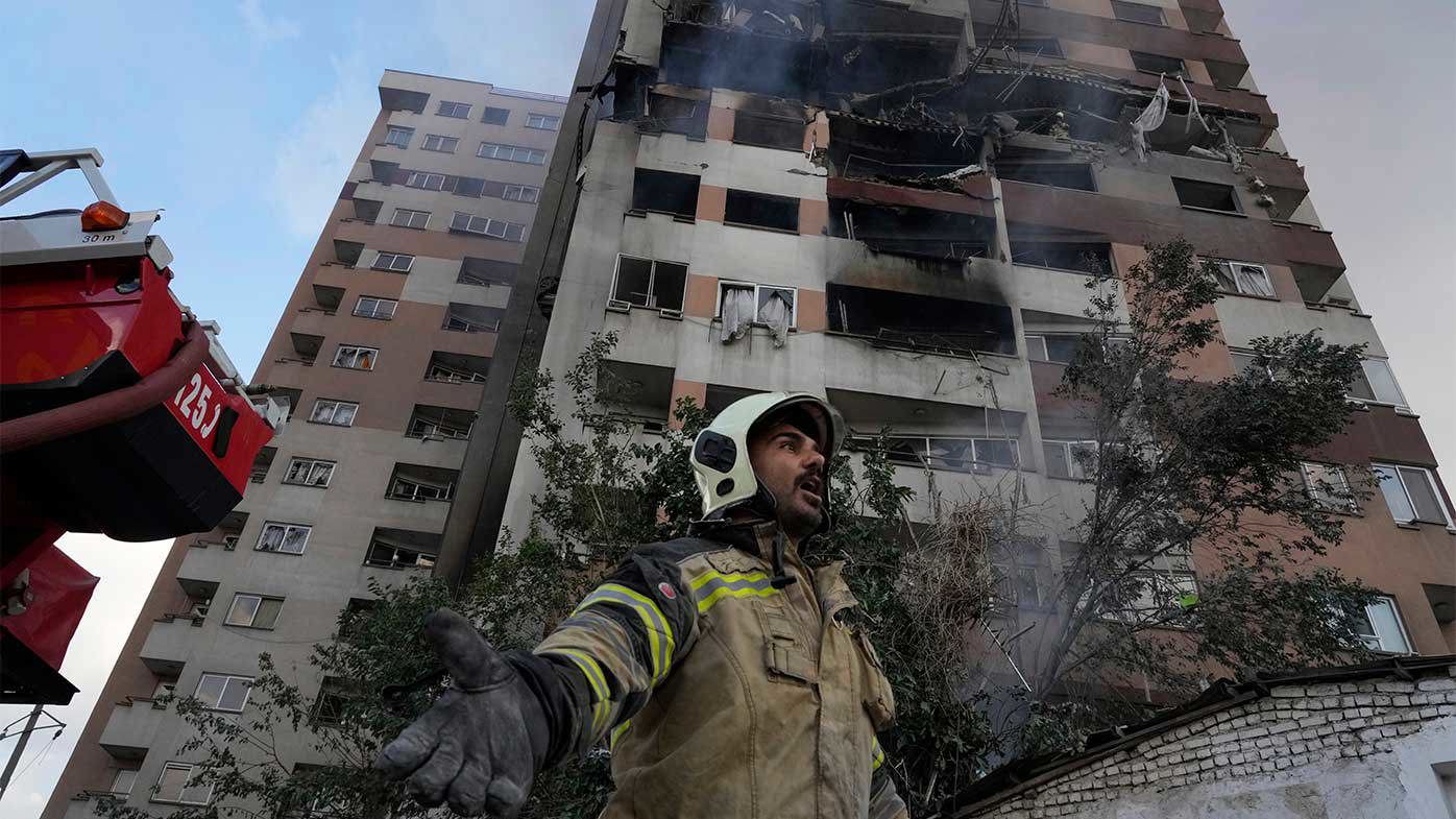 A firefighter calls out his colleagues at the scene of an explosion in a residence compound in northern Tehran, Iran.