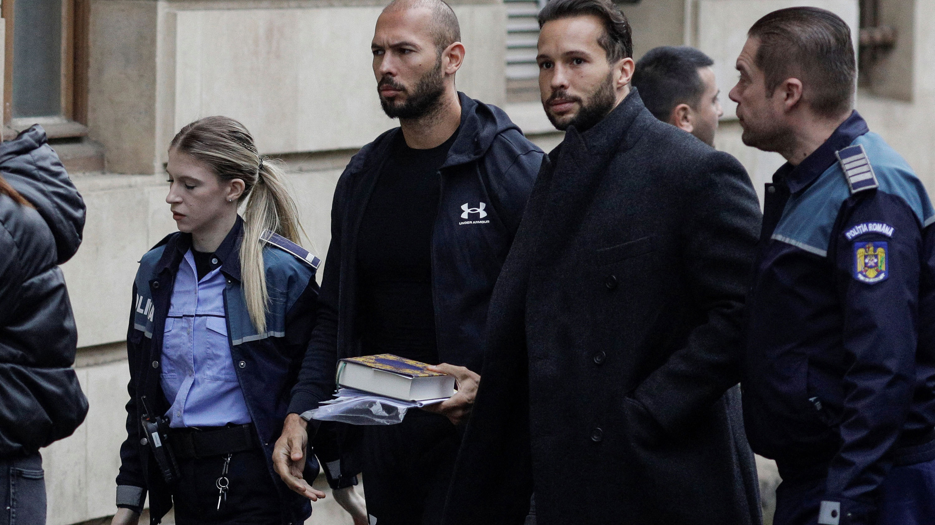 Andrew Tate and his brother Tristan are escorted by police officers outside the headquarters of the Bucharest Court of Appeal, in Bucharest, Romania.