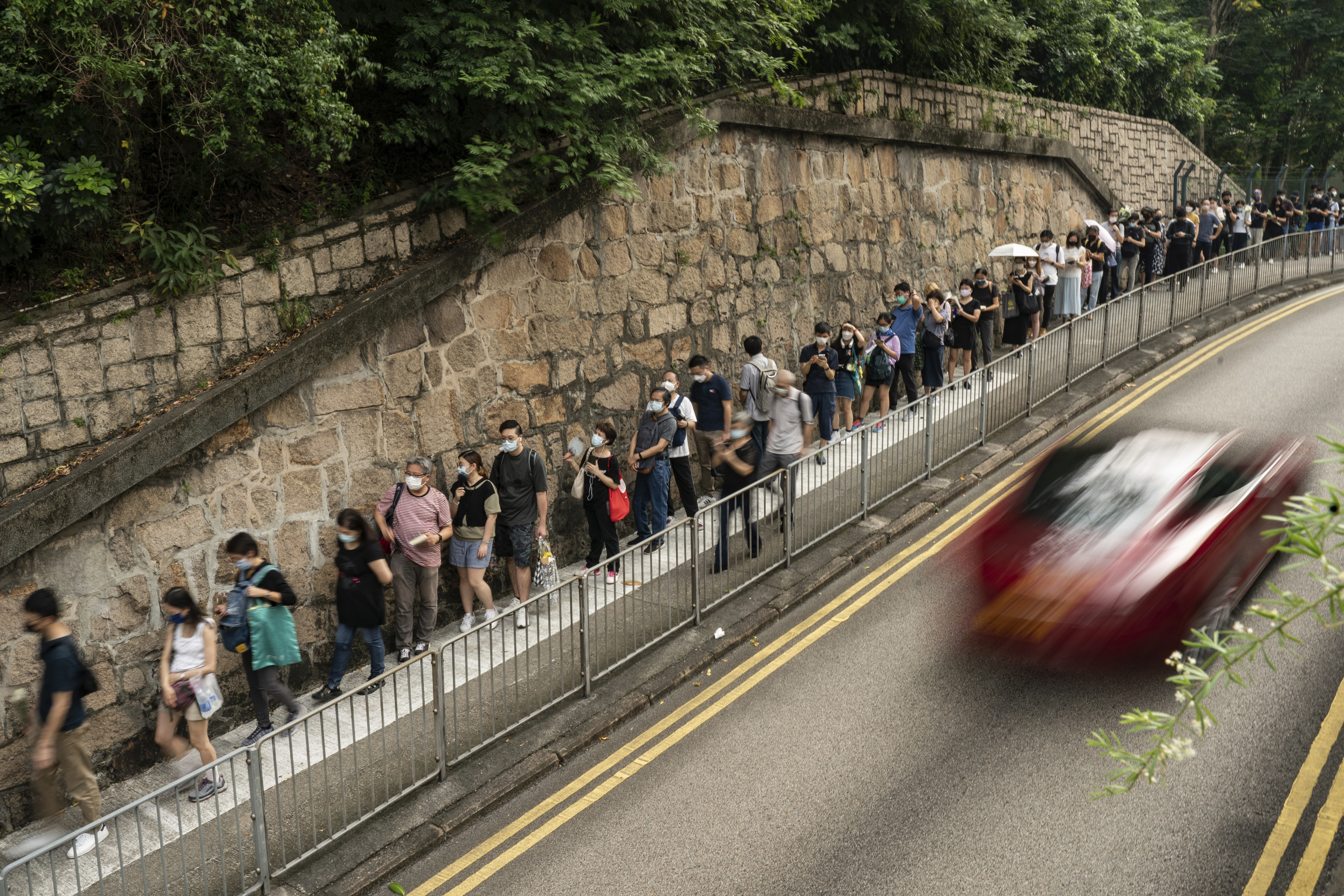 People wait in line to pay tribute to Queen Elizabeth II outside the British Consulate in Hong Kong, Friday, Sept. 16, 2022. 