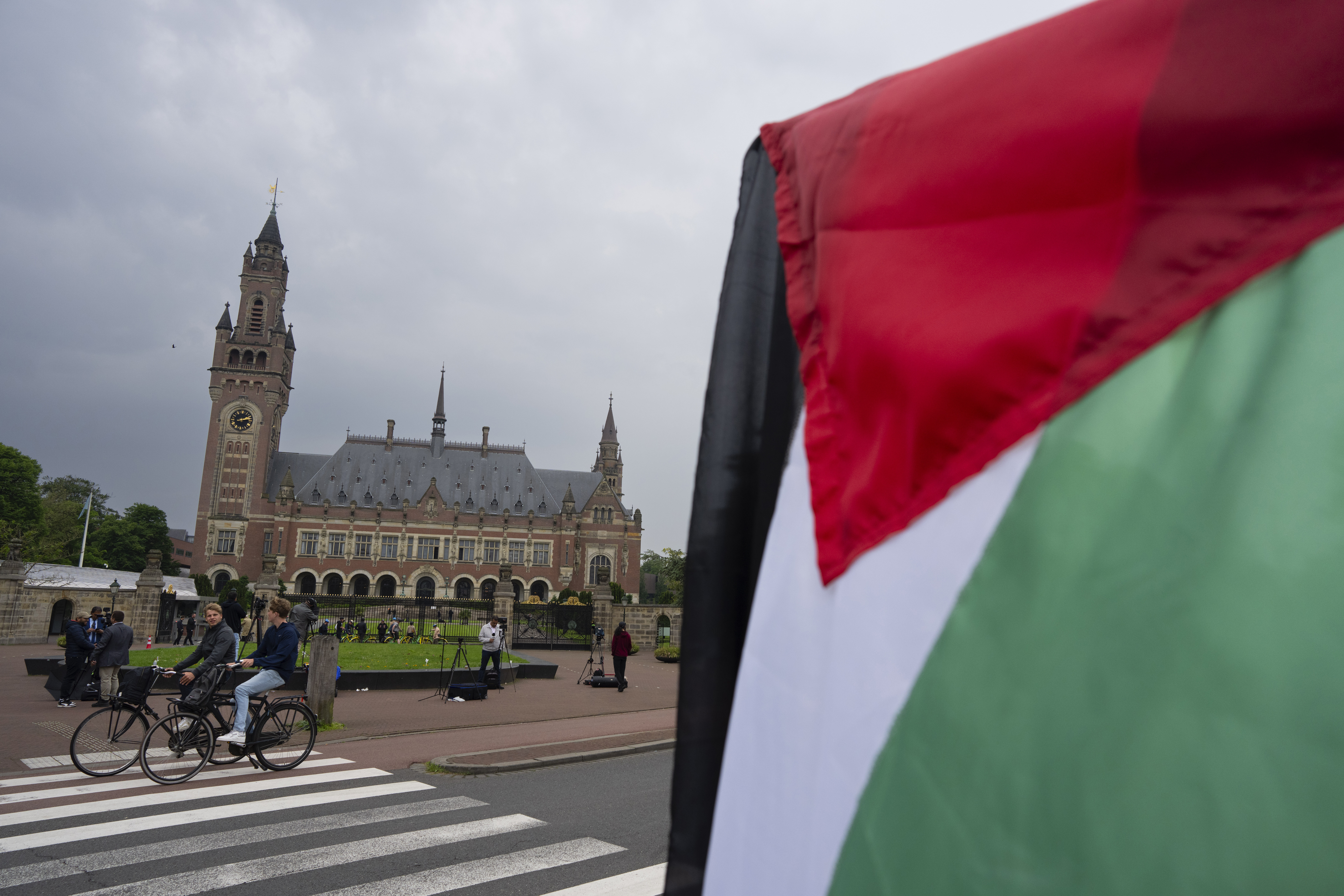 A lone demonstrator waves the Palestinian flag outside the Peace Palace, rear, housing the International Court of Justice, or World Court, in The Hague, Netherlands, Friday, May 24, 2024. 