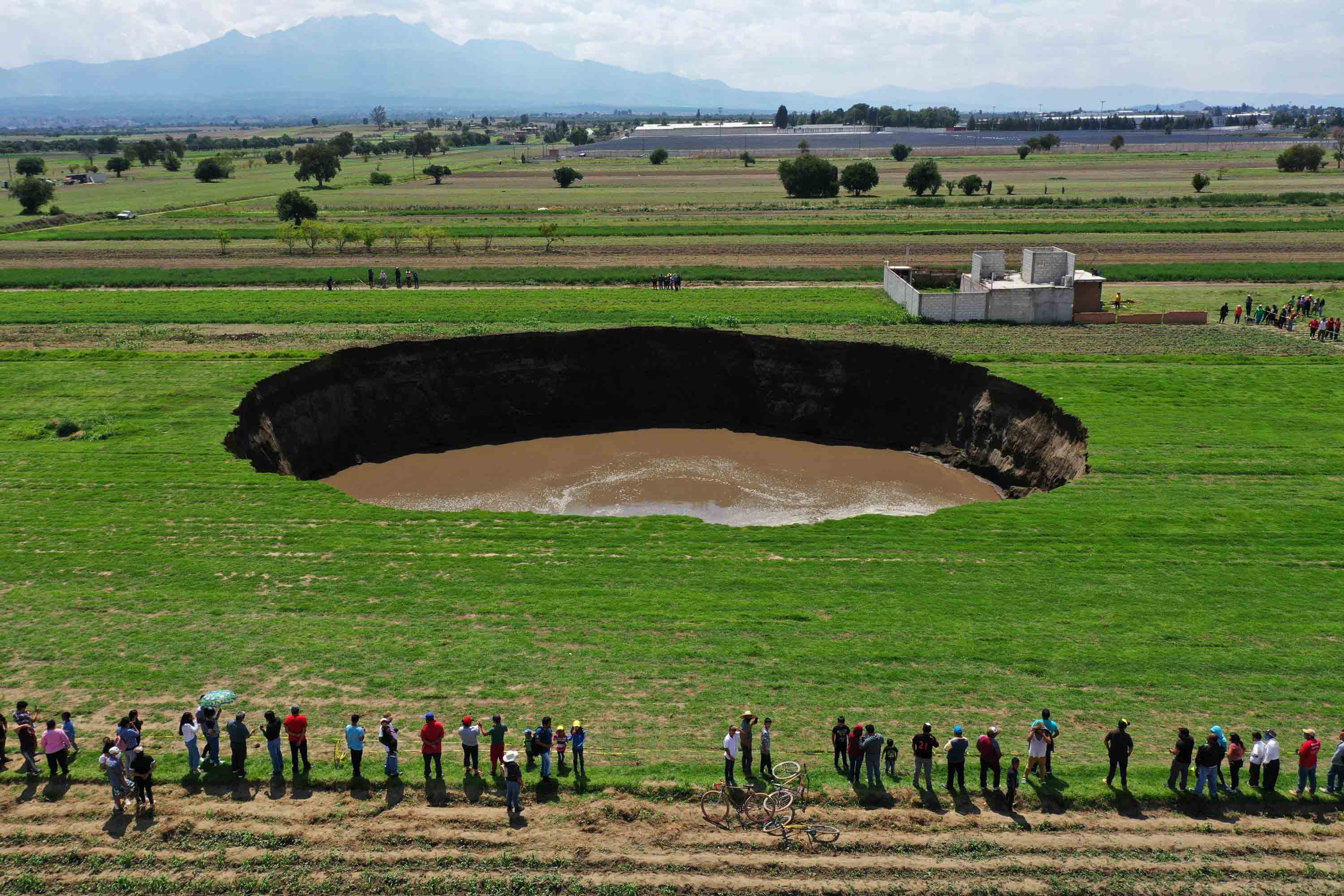 People gather to look at the giant sinkhole that opened up this week in central Mexico. 