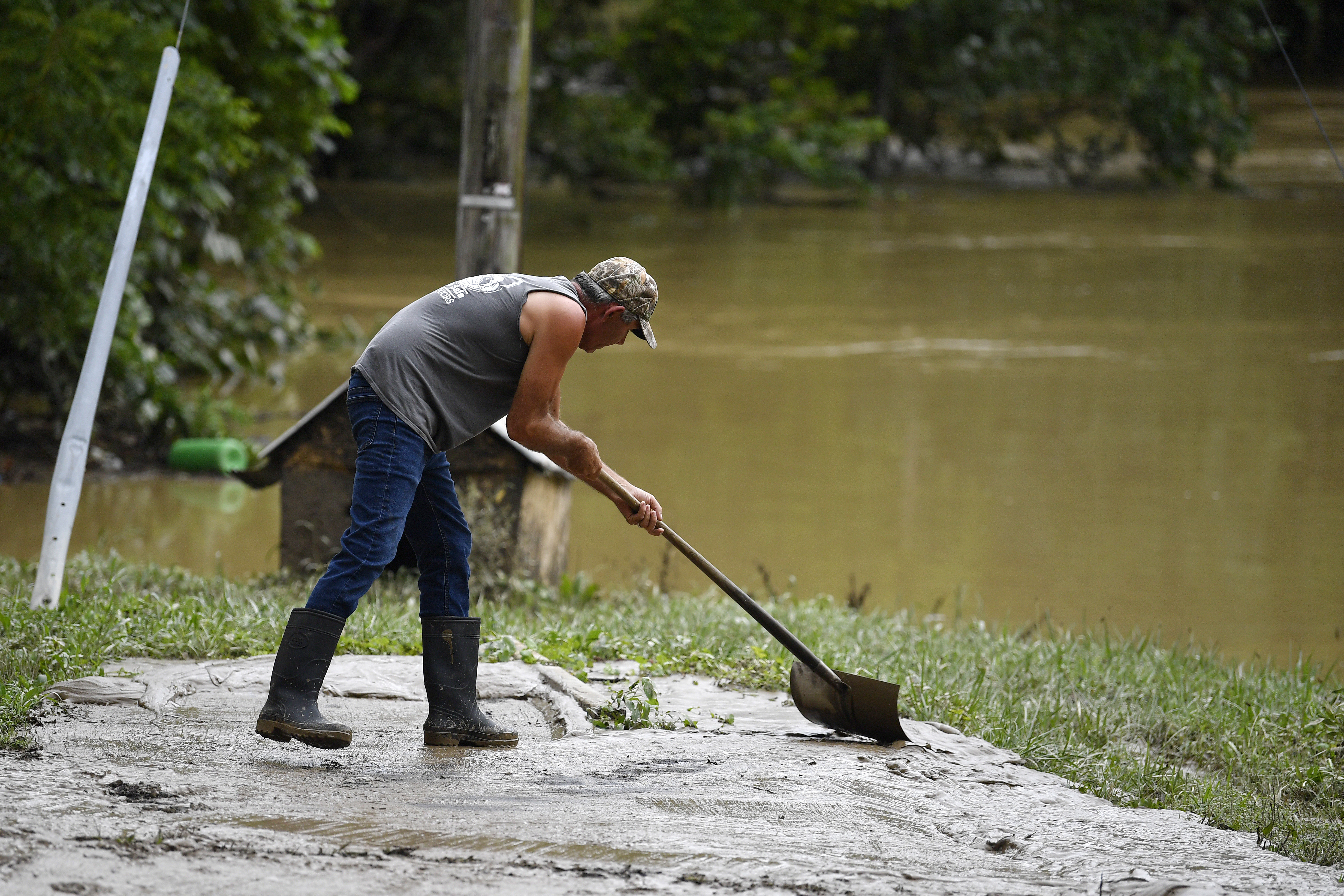 Junior Bowling shovels mud and silt from receded floodwaters in Jackson, Ky., Friday, July 29, 2022. Floodwater from the North Fork of the Kentucky River came within inches of getting inside his home. (AP Photo/Timothy D. Easley)