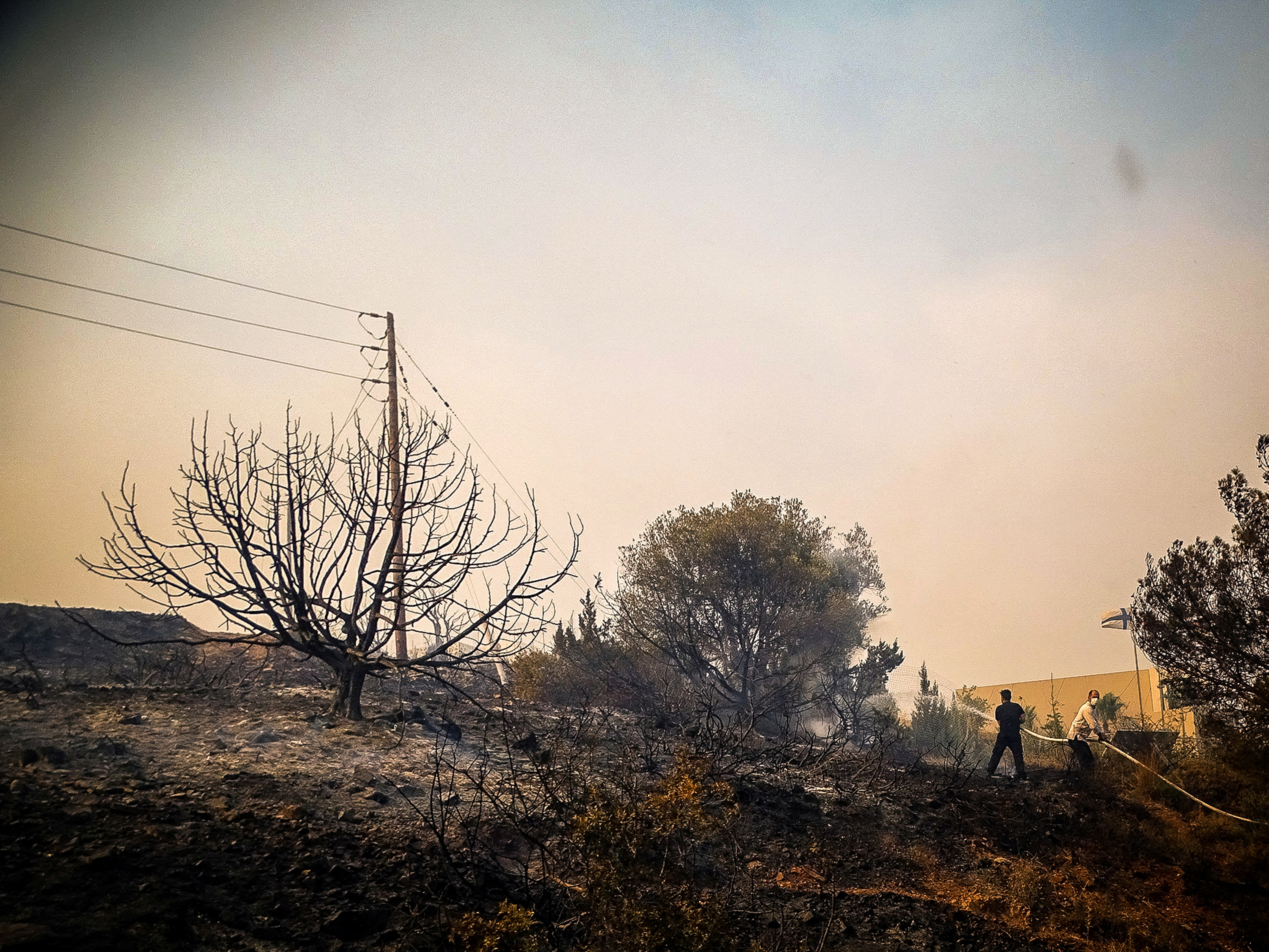 People try to extinguish a wildfire on the island of Rhodes, Greece, July 22, 2023. 